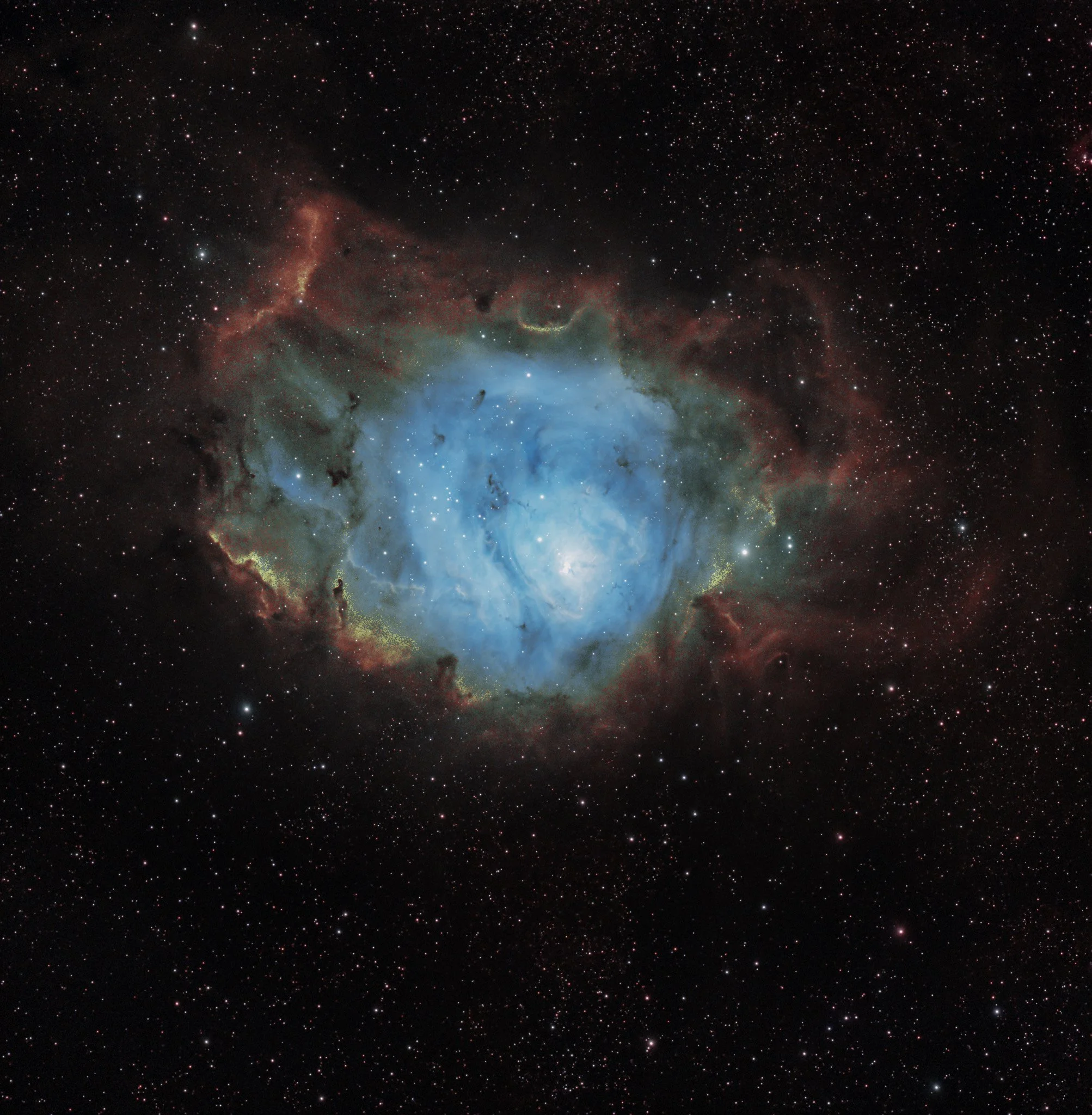 Glowing blue core and surrounding red dust lanes of the Lagoon Nebula captured against a dense field of stars.