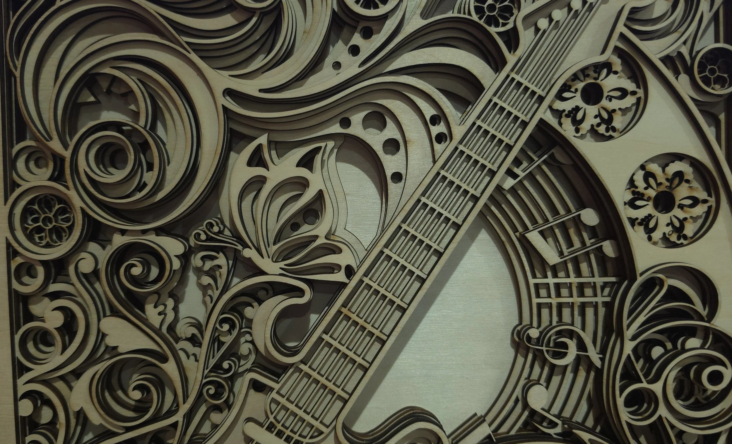 Close-up of laser-engraved 3D wooden guitar cover with musical notes and swirl accents..jpg