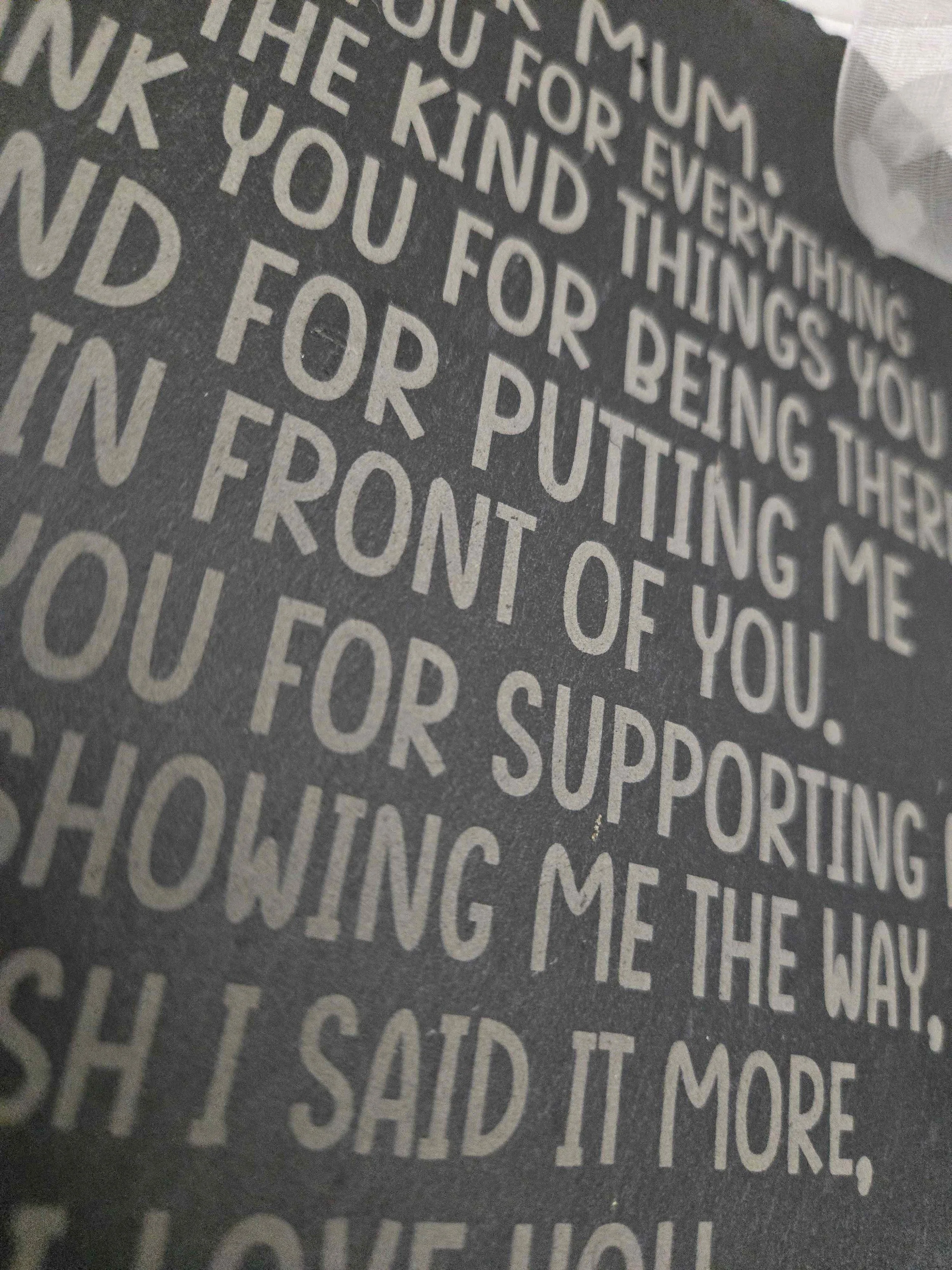 Close up of deep laser engraving on textured Welsh slate showing high contrast text.