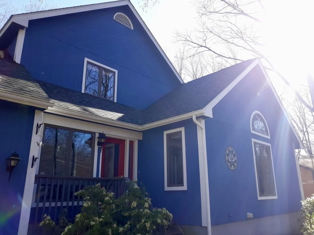 A blue two-story house with white trim, large windows, and a new roof and new siding. Milford, PA