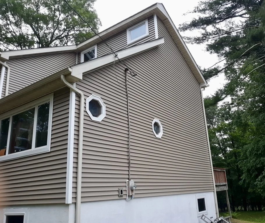 The exterior of a beige house with vinyl siding and a NEW roof in Lords Valley, PA.