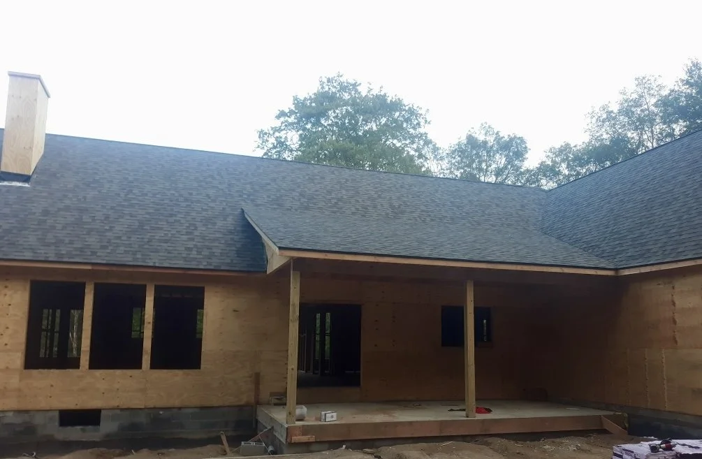 Under construction wooden house with a NEW dark shingled roof in Montague NJ.