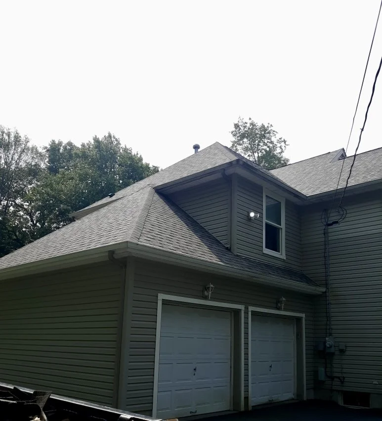 Side view of a house showing a pitched roof, a window in the upper level. New roof in Honesdale, PA.