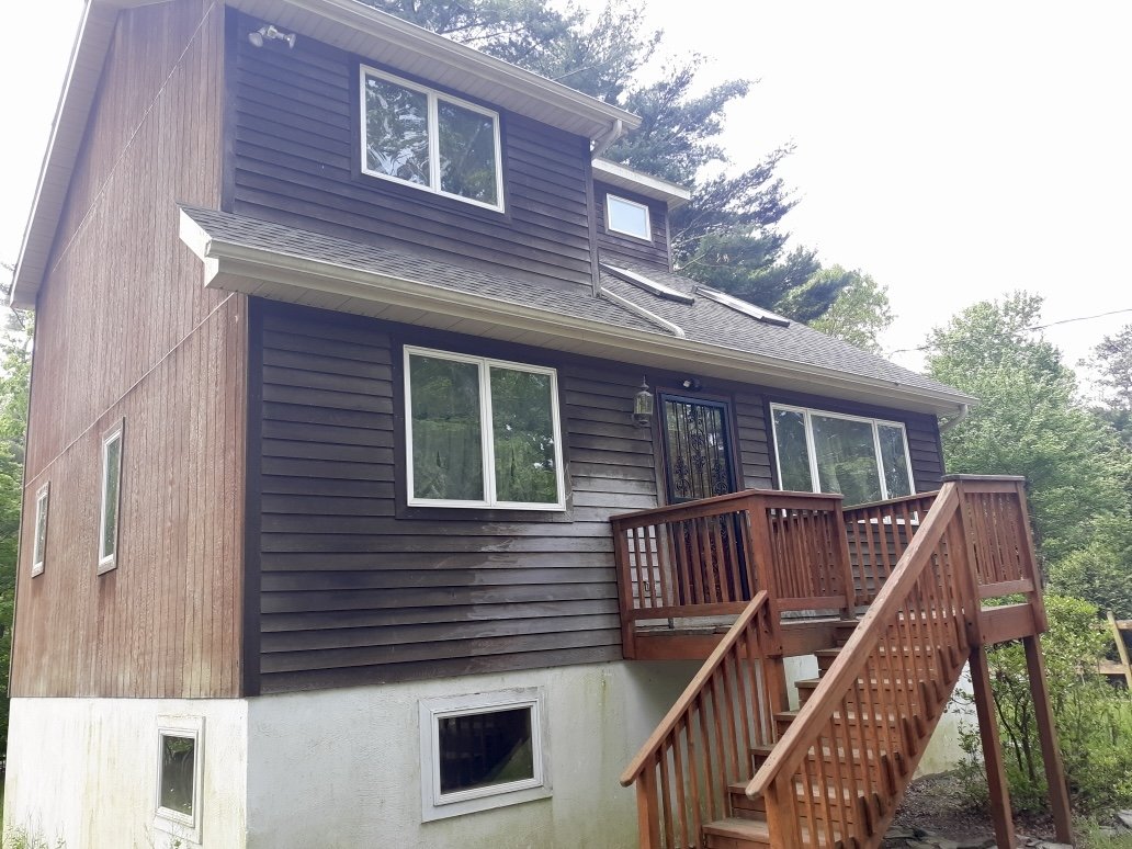 A two-story house with dark brown and light brown exterior siding, multiple windows, and a new roof in Milford, PA.