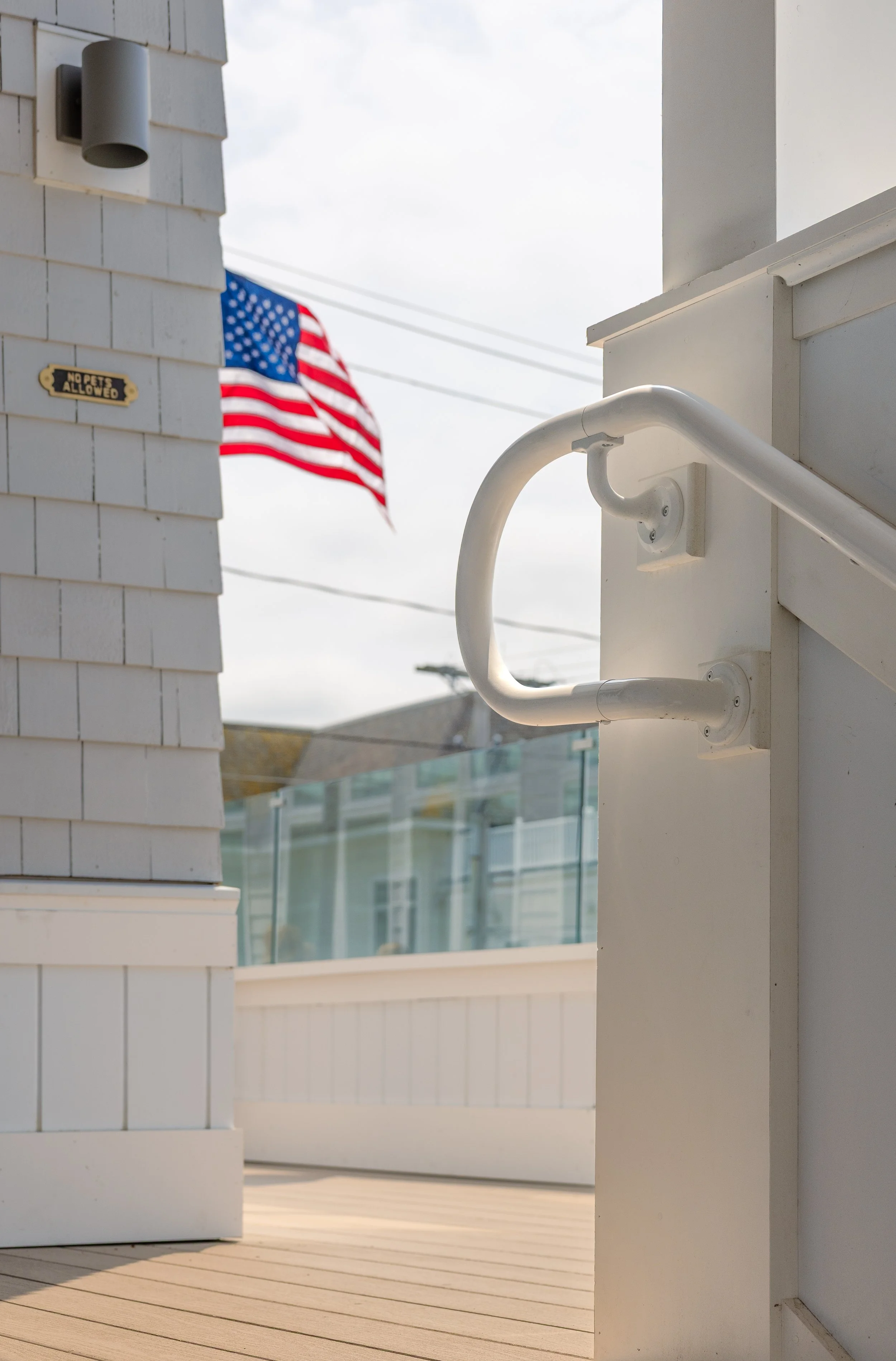 An American flag on a flagpole outside a white building with a white railing and a 