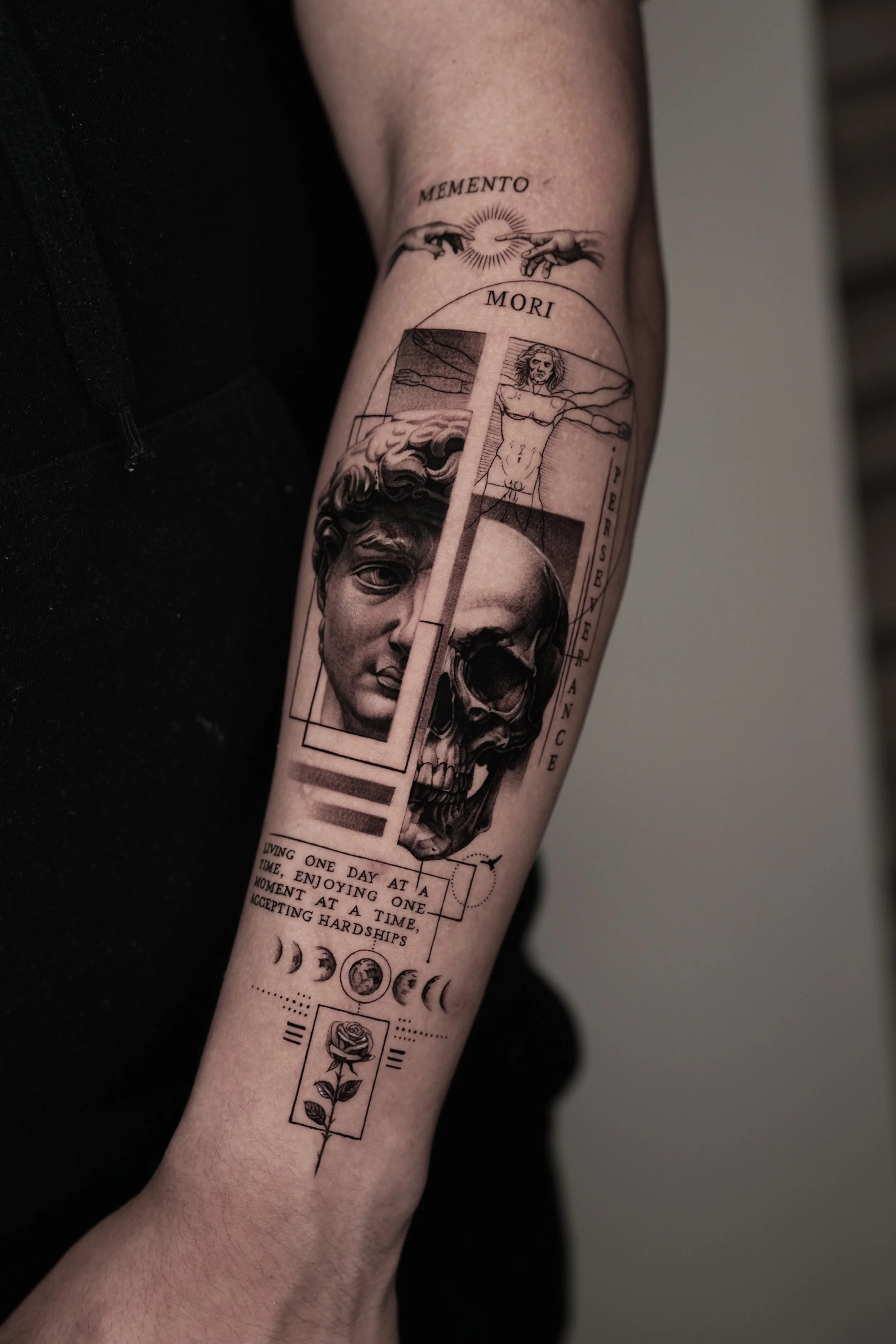 Black and gray tattoo featuring a classical sculpture of a woman's face, a human skull, a figure of a woman with outstretched arms, the words "Memento Mori," a quote about living and accepting hardships, phases of the moon, the moon phases, and a ros