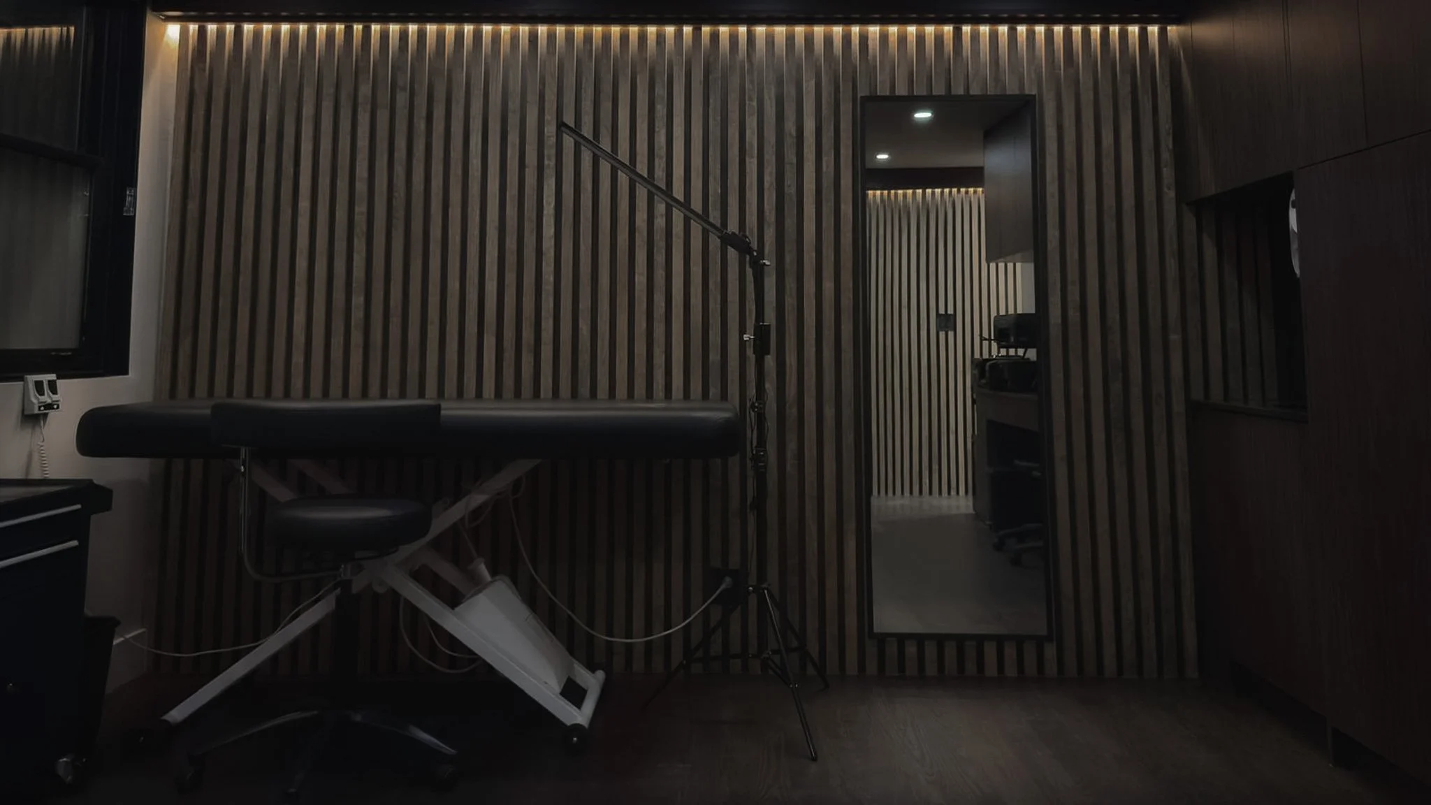 Modern tattoo studio interior with a chair, wooden panel walls, and soft lighting.