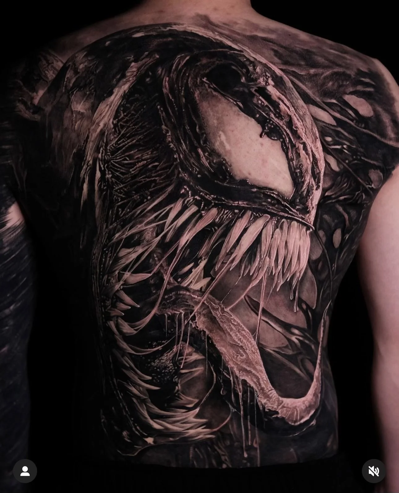 Back tattoo of a menacing creature with sharp teeth and an open mouth, featuring intricate shading and details.