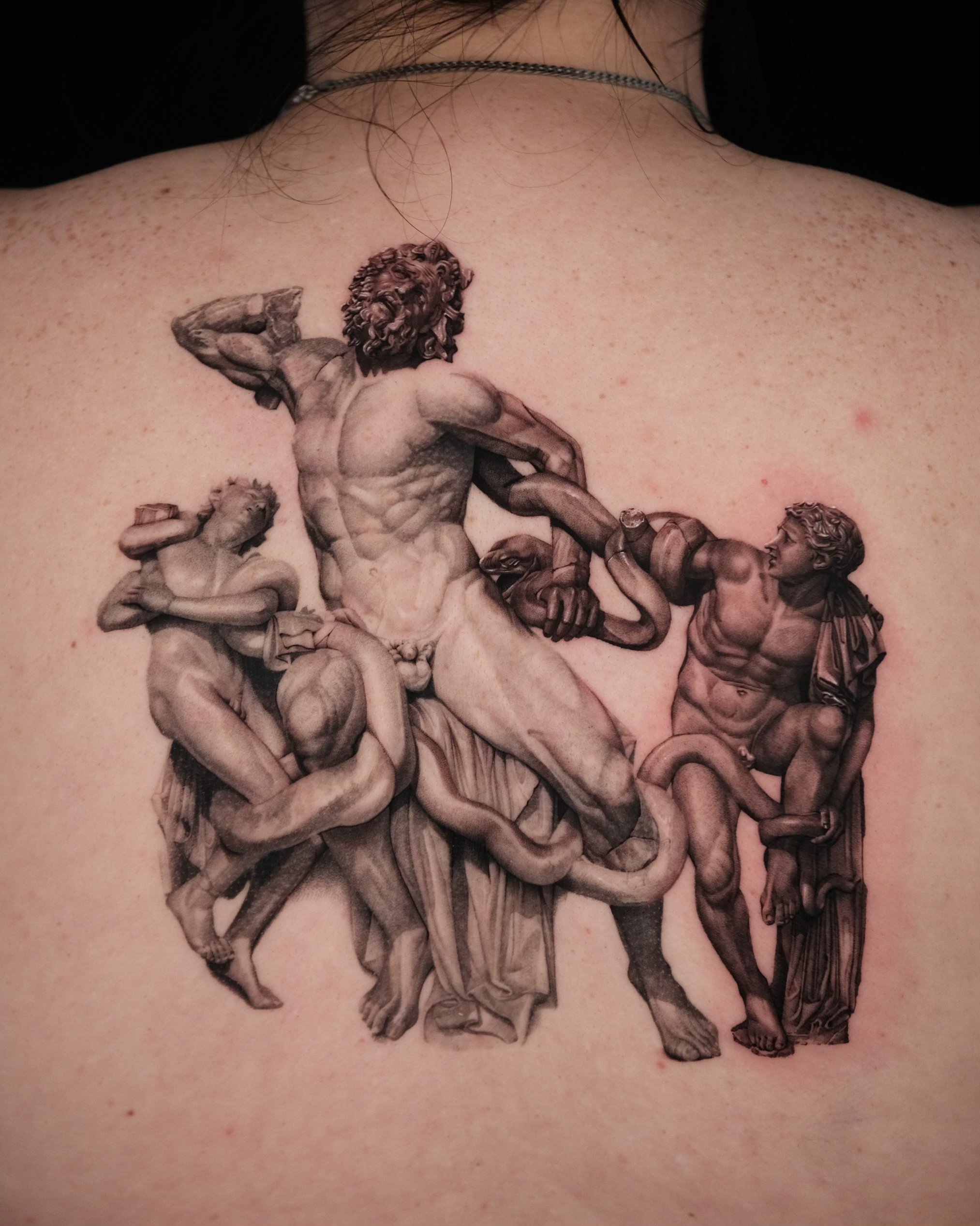 Tattoo of the Laocoön and His Sons sculpture on a person's back.