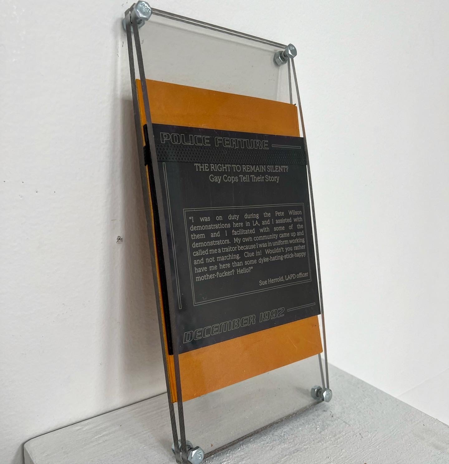 Report!, 2020, news article police report etched onto anodized aluminum, leather, polycarbonate, 14" x 6" x 3"