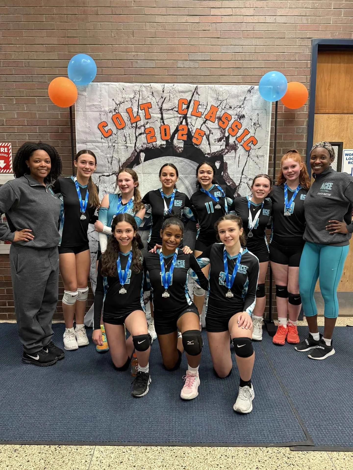 A group of girls in volleyball uniforms and medals poses in front of a backdrop that says 'Colt Classic 2025'.