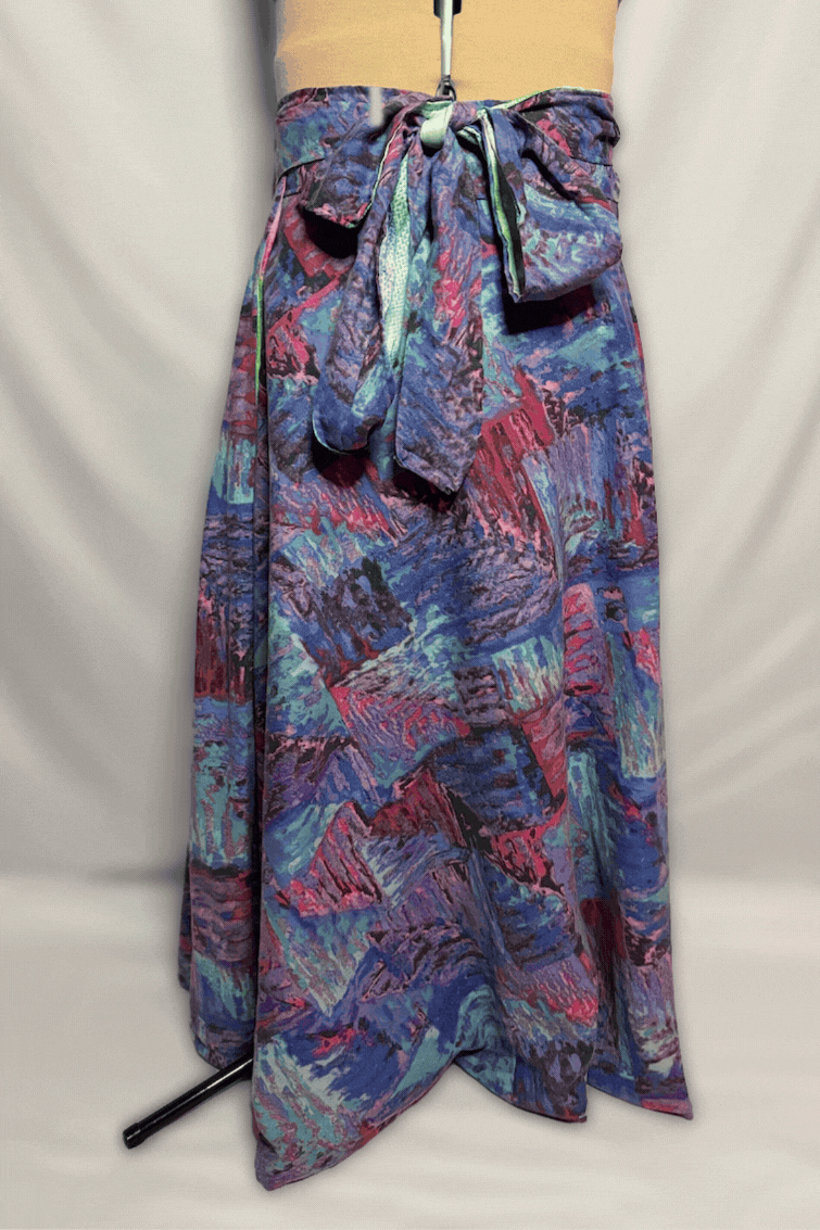 A mannequin wearing a yellow top with a colorful abstract-patterned skirt tied at the waist, displayed against a plain background.