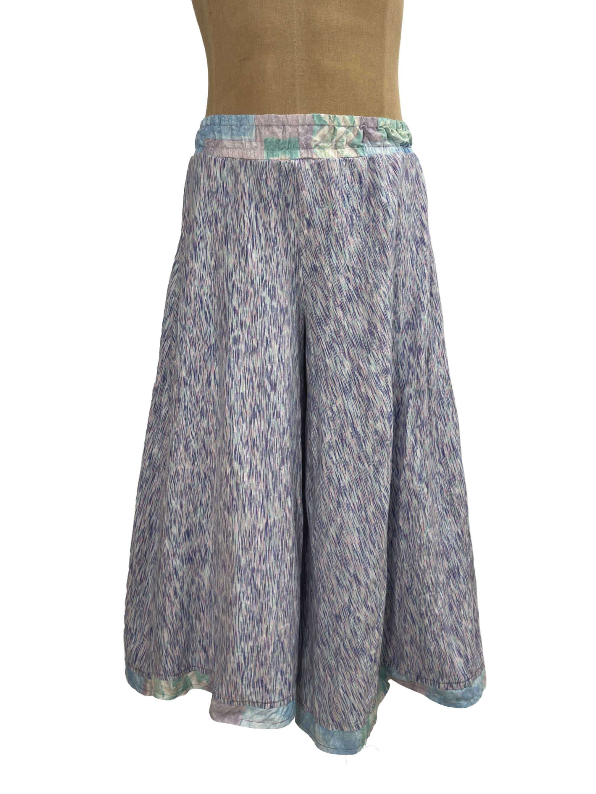 Wide-leg palazzo pants in a purple space-dyed print with a pastel patchwork elastic waistband, shown on a dress form..