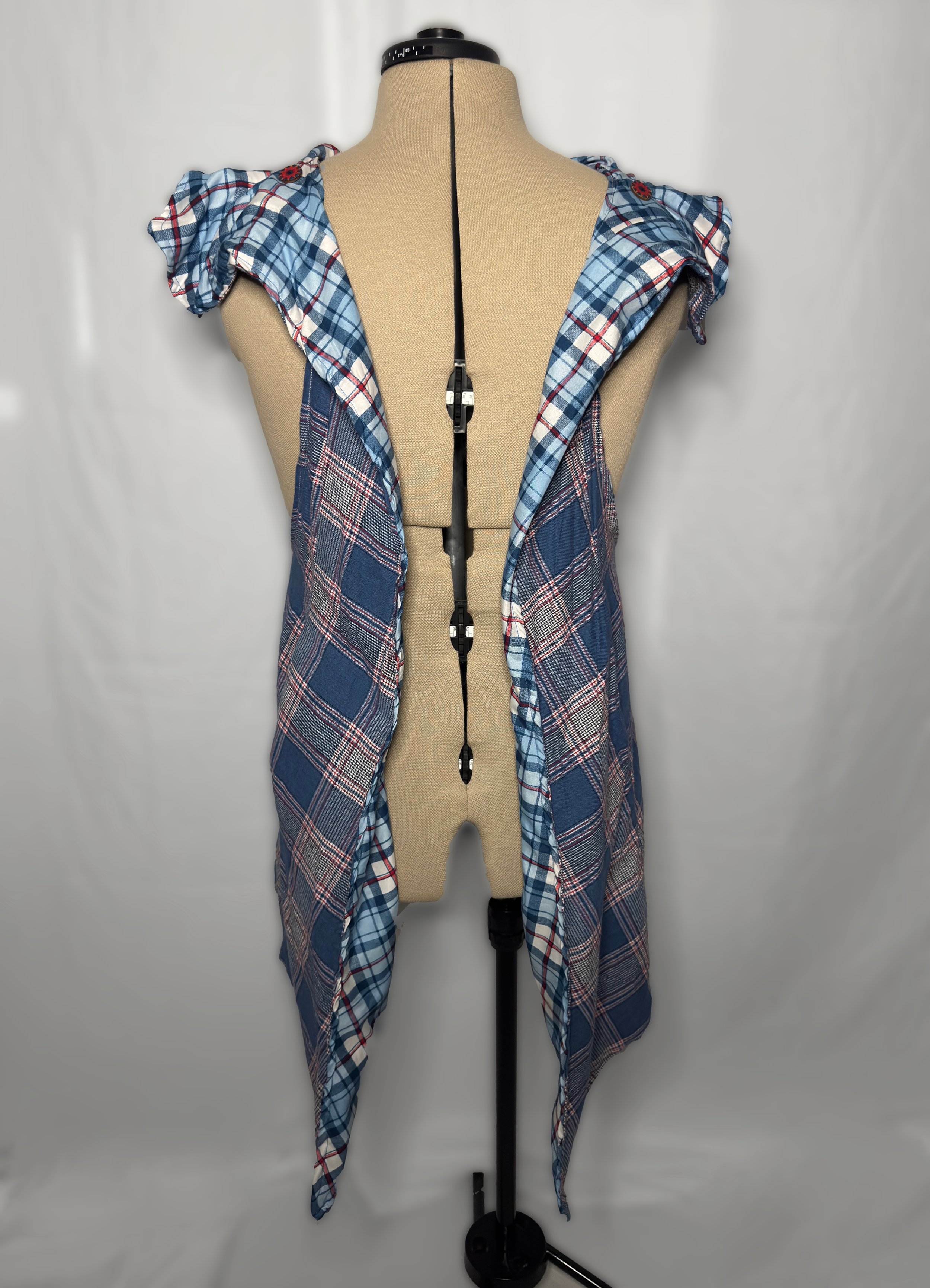 Dress form wearing a plaid and checkered shirt with ruffled sleeves in shades of blue, red, and white.