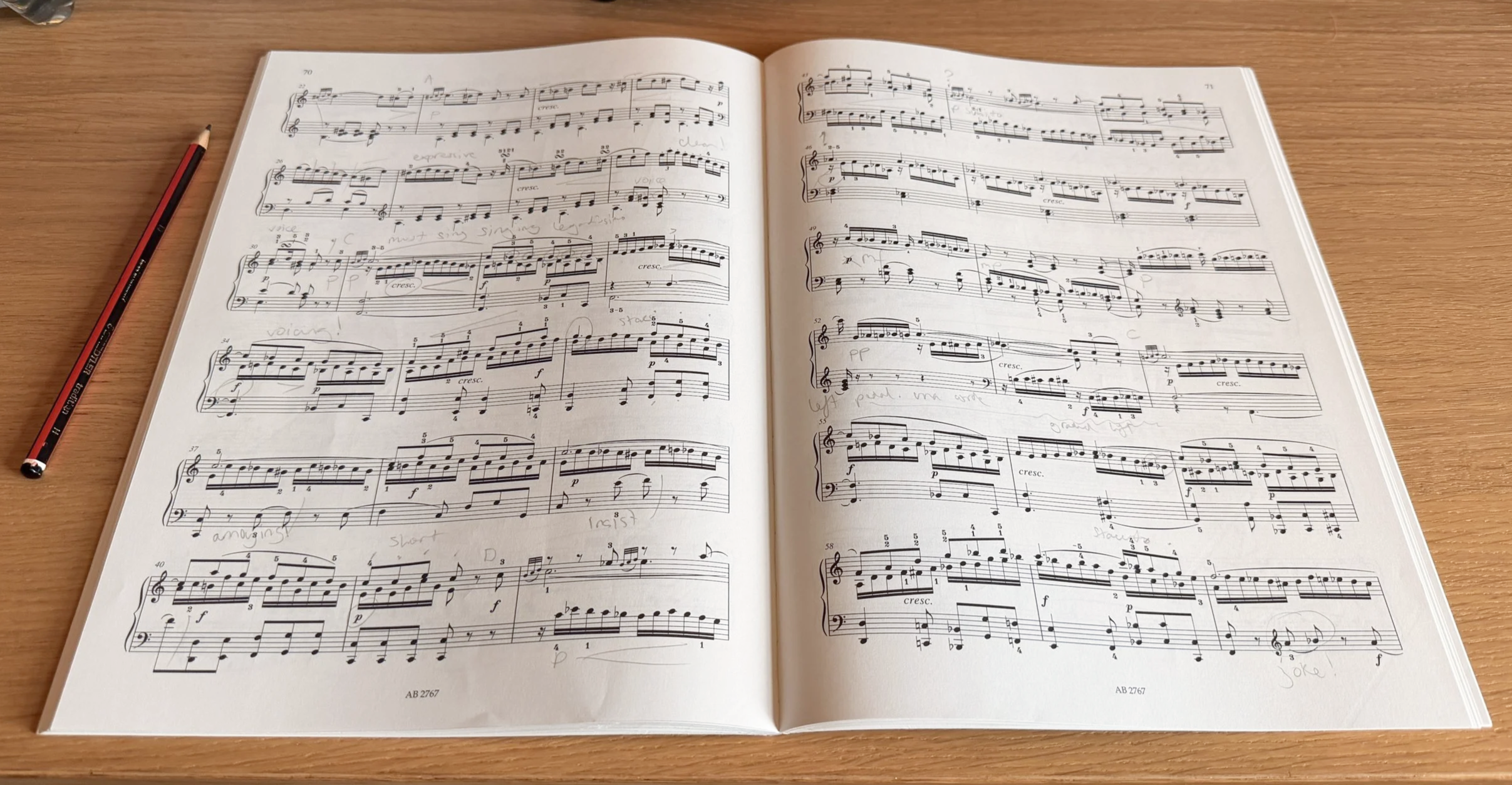 An open, annotated Mozart Rondo in A Minor lying on a wooden table with a red and black pencil placed on the left side.