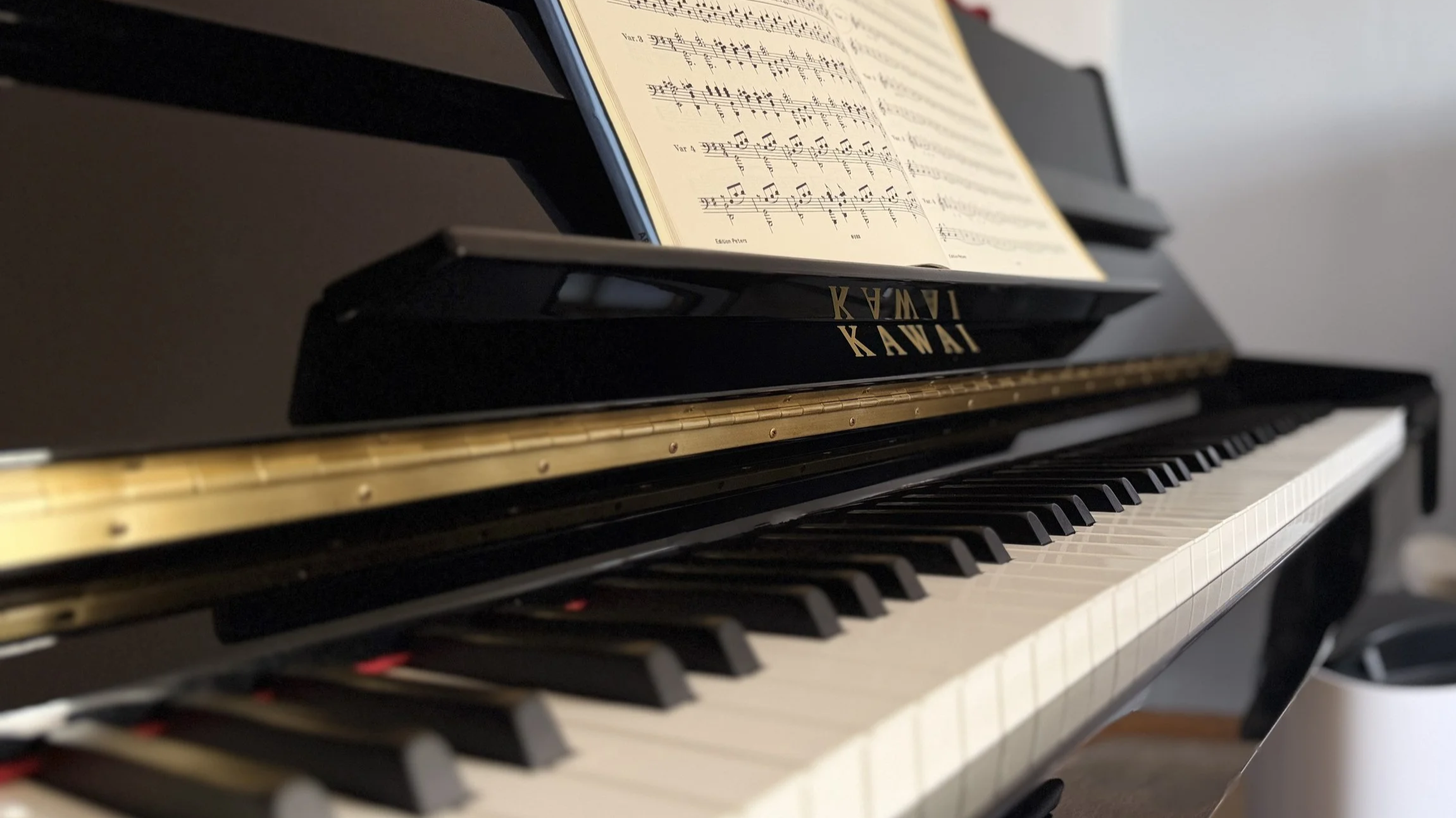 Close-up of a Kawai upright acoustic piano with Beyer's Preparatory School on the stand, showing a clean, tidy background.