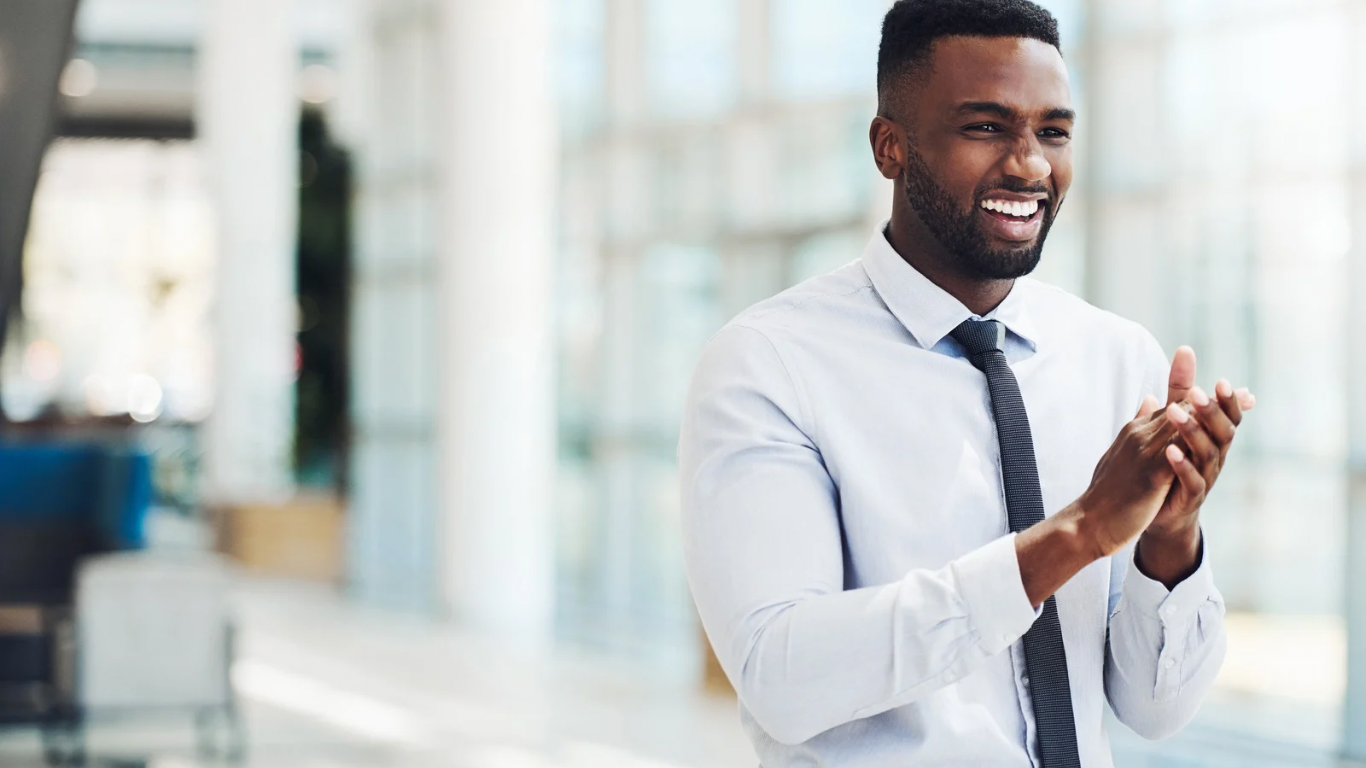 Man in a business setting smiling confidently, representing attachment-informed leadership and workplace emotional safety.