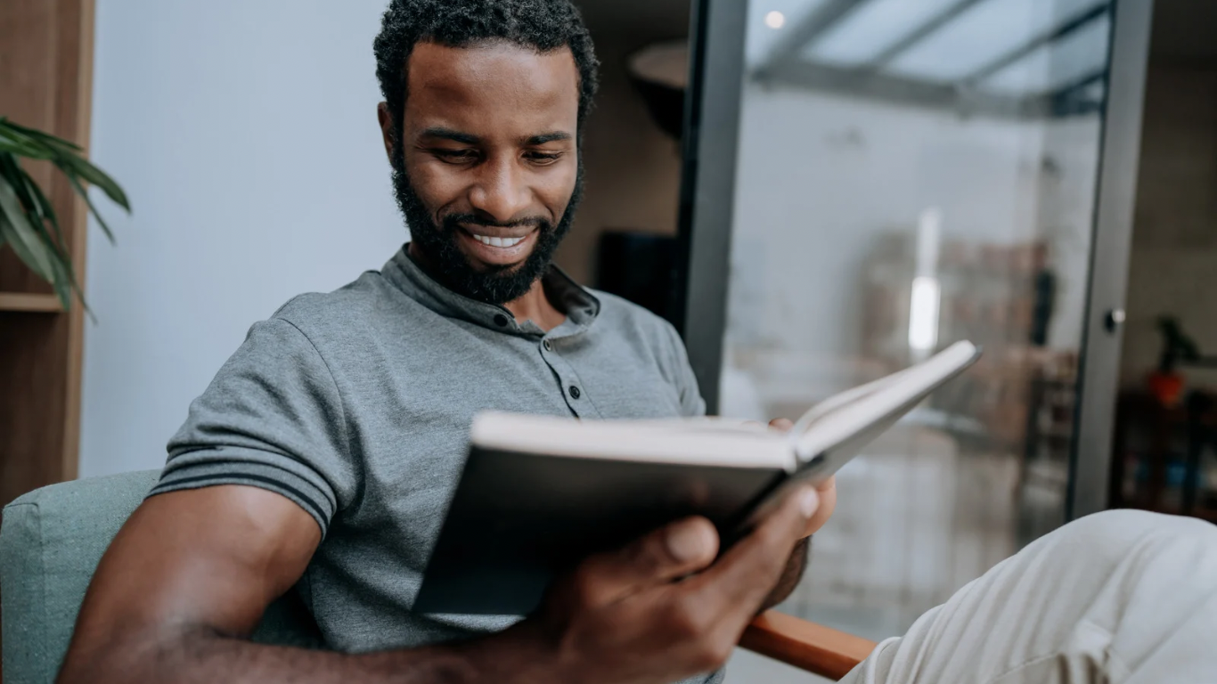 Man reading a book while sitting in a chair indoors.
