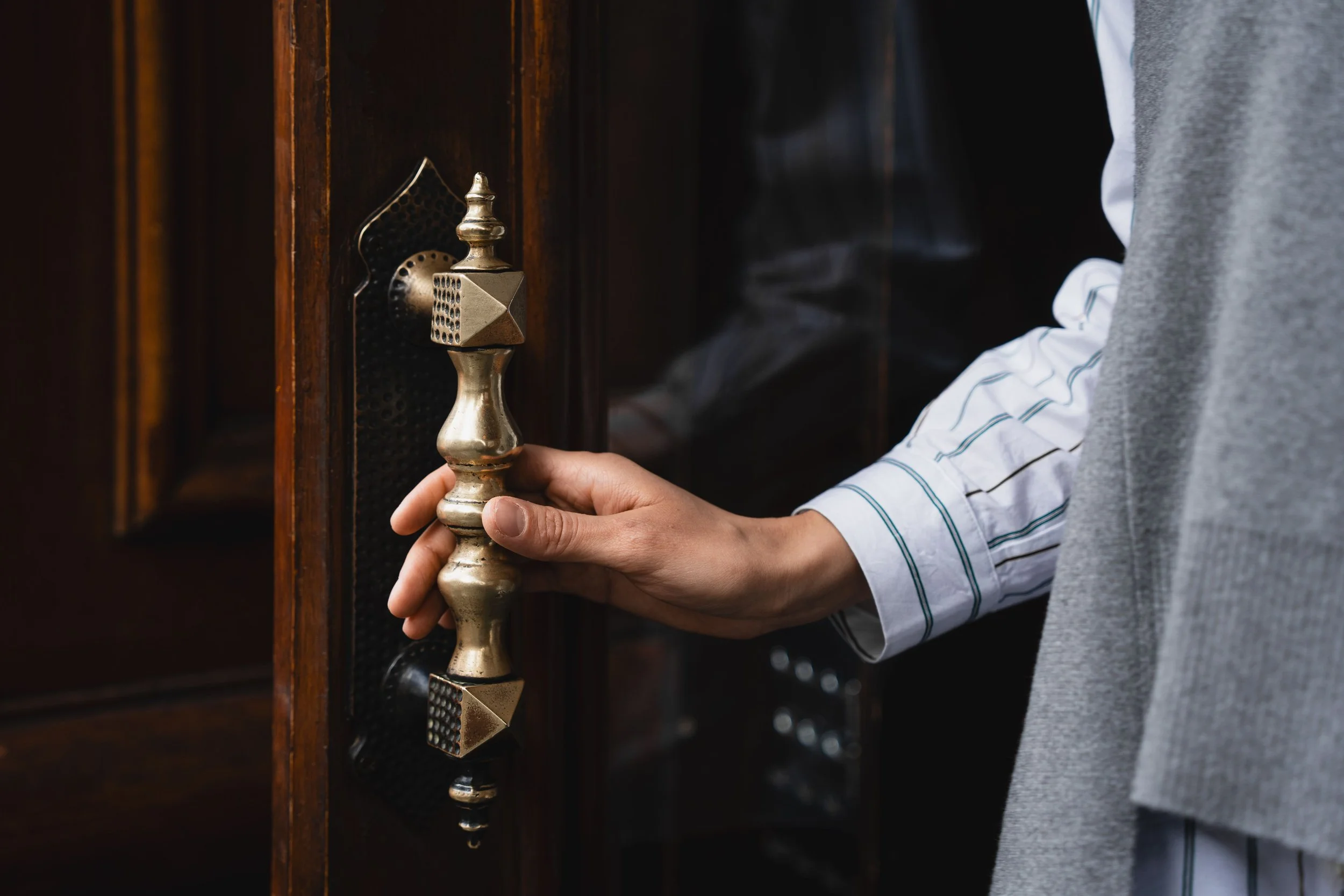 A person pausing at a doorway with an unreadable expression, representing the space between staying and leaving.