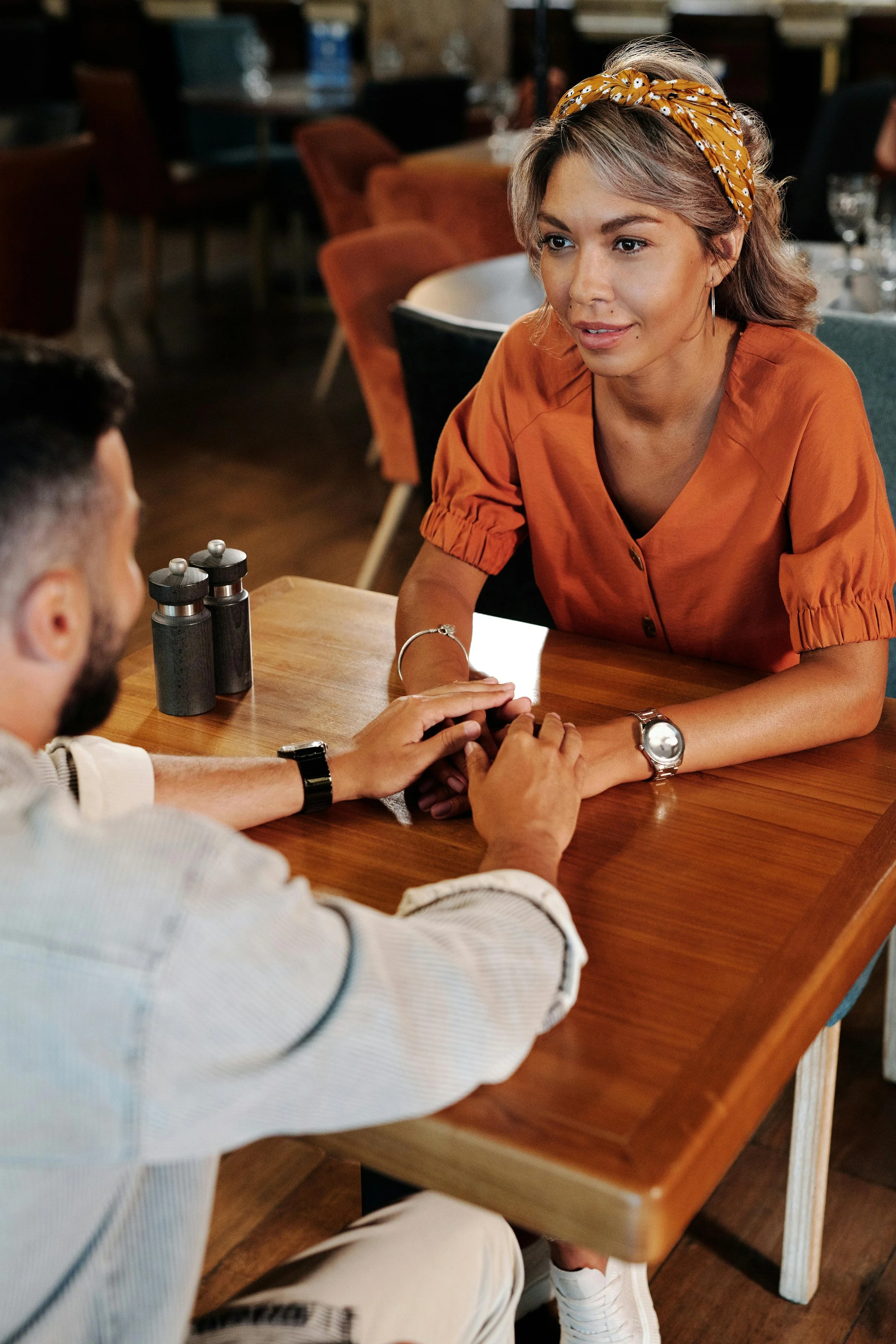 A woman sitting across from someone at a café, present in a difficult conversation — holding grief and connection at the same time