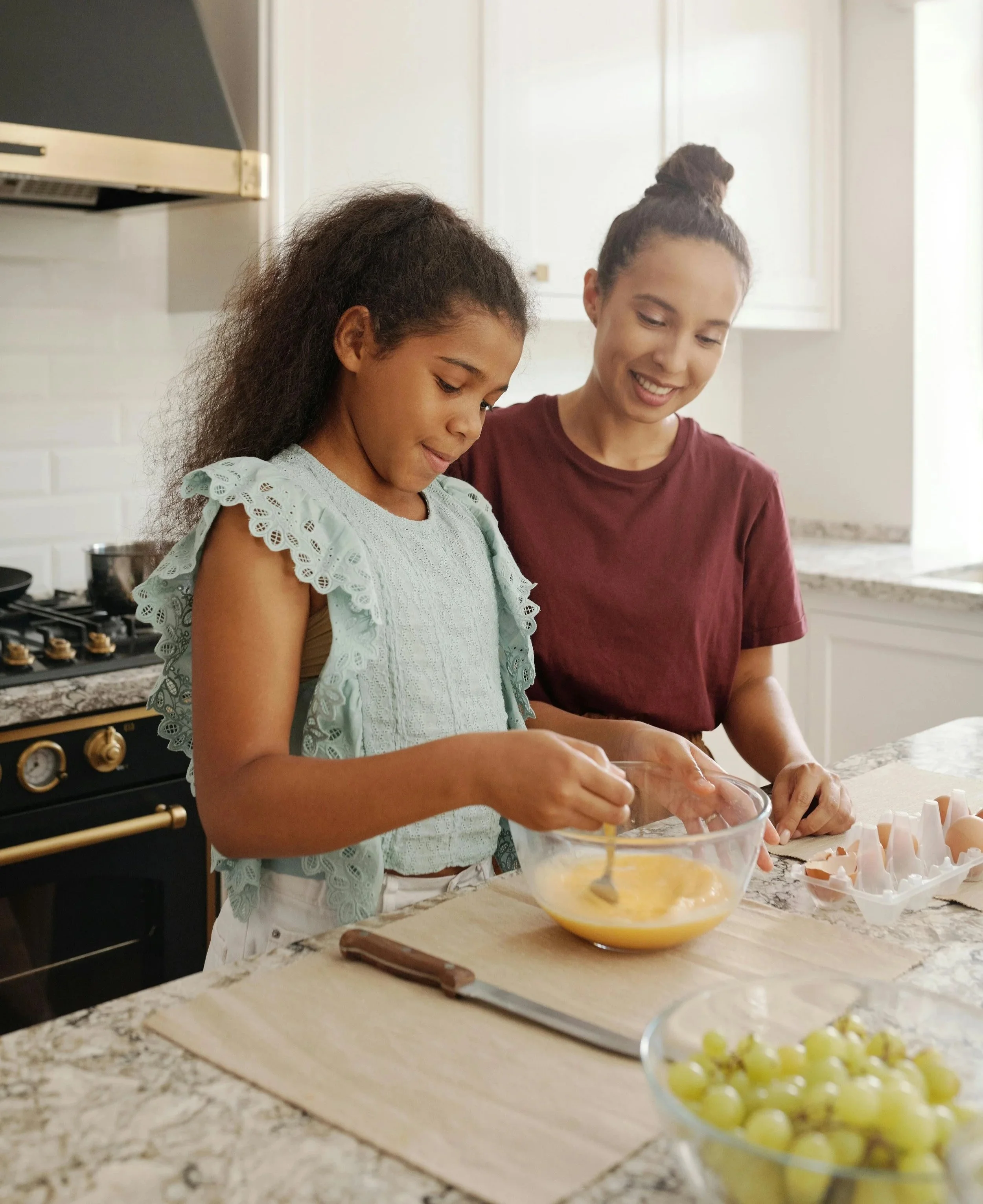 Mother and daughter preparing a meal together in a kitchen, reflecting everyday moments where attachment patterns show up in parenting.