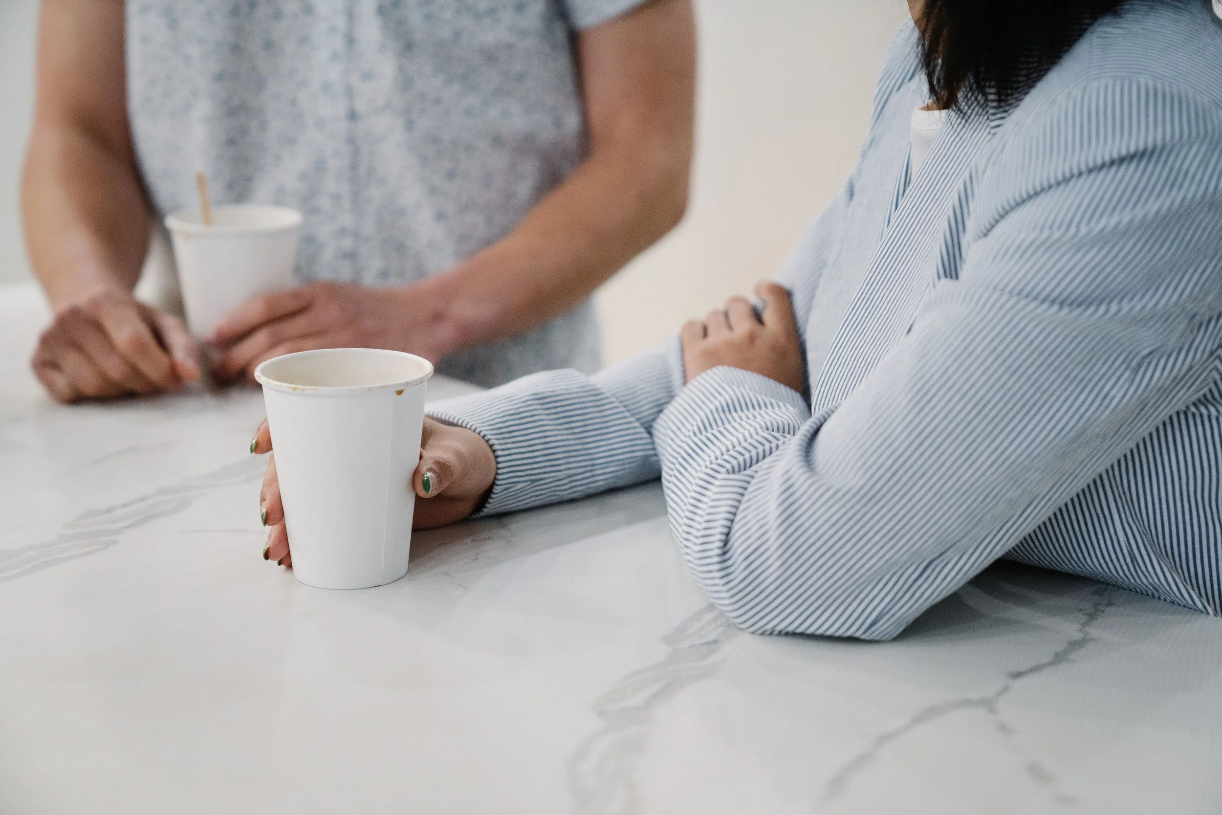 Two women sitting together over coffee, representing the shape of a relationship where one person has grown and the other hasn't.