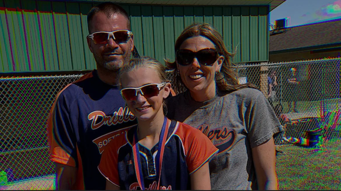Lauryn Licari in a softball uniform standing between her mother, Colleen Licari, and father, Jim Licari.