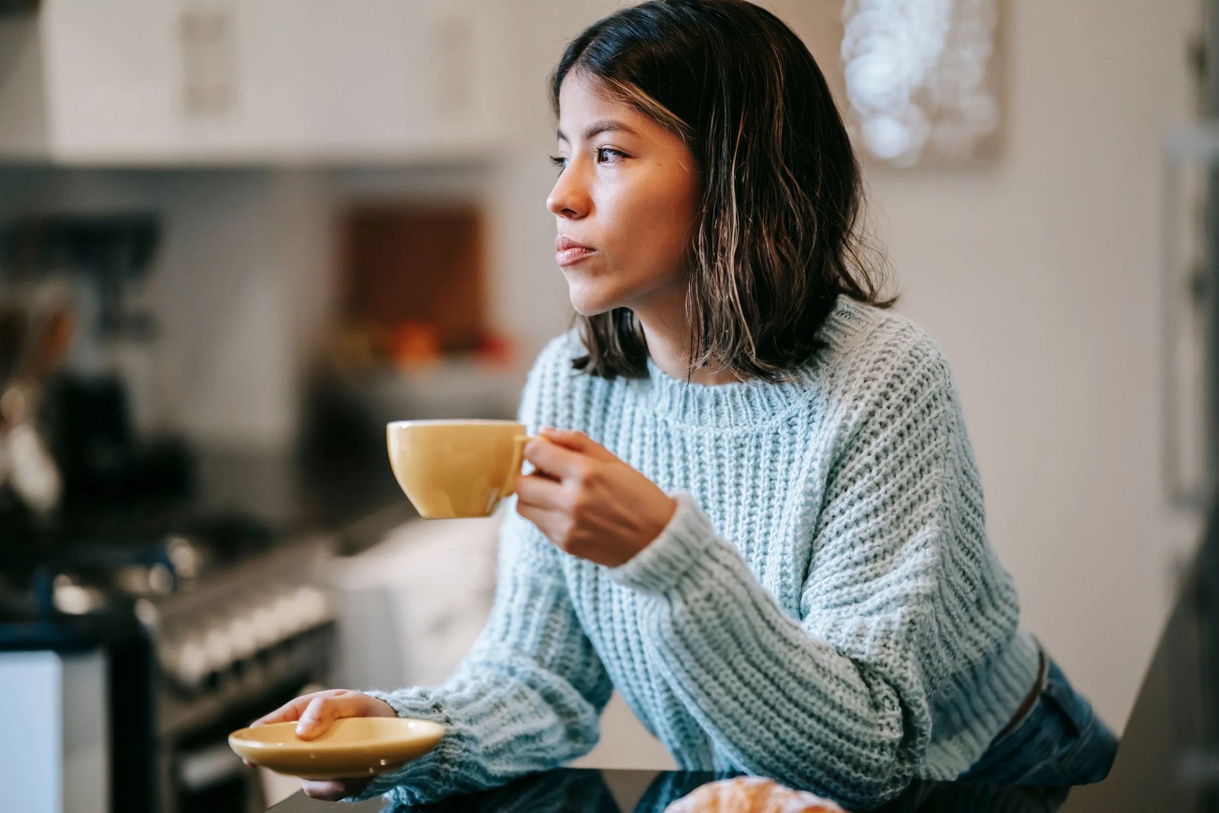 A person sitting quietly with a coffee mug, representing the recognition of a family pattern they haven't named before.