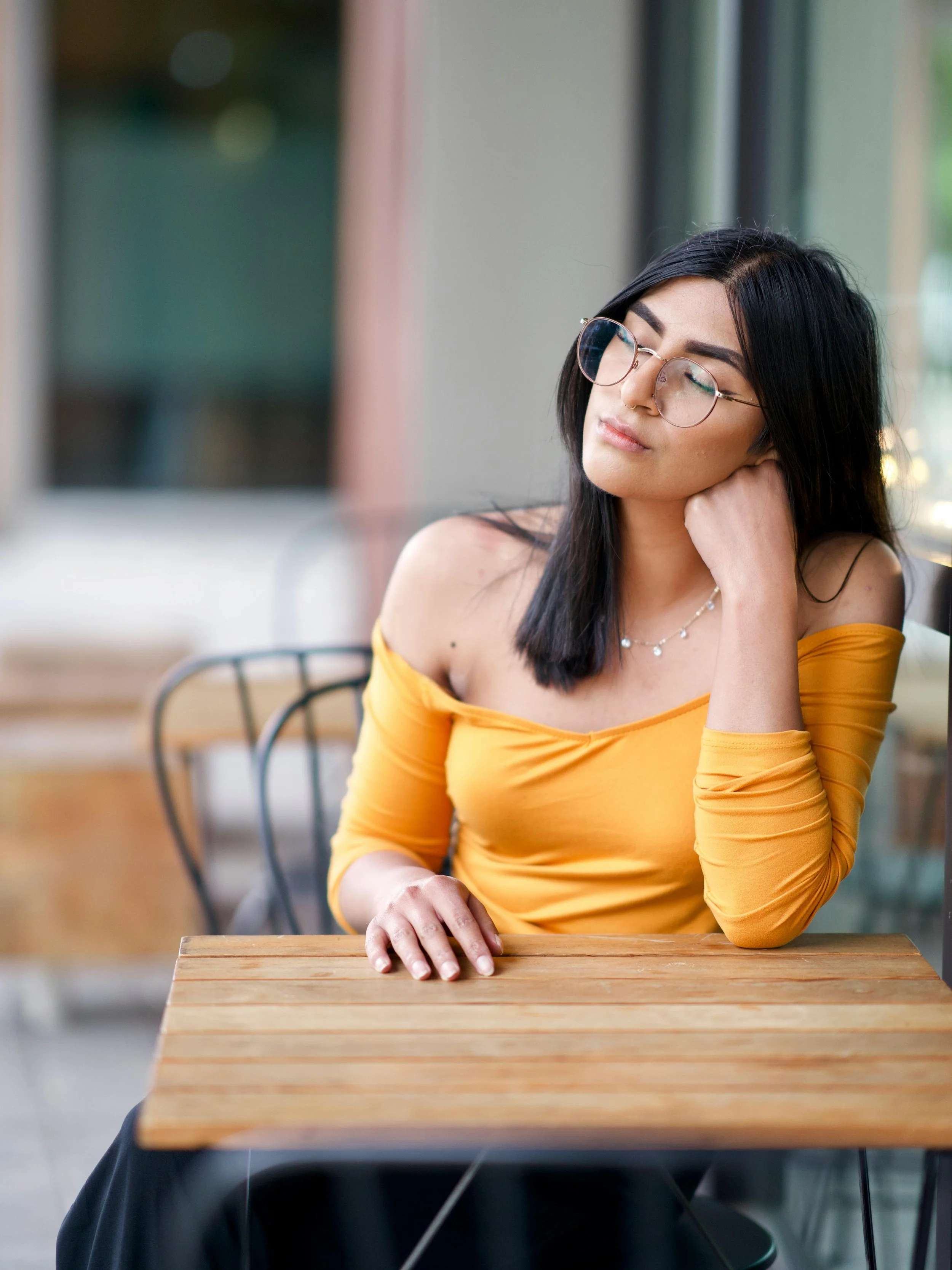 A woman with glasses and dark hair, eyes closed, head tilted back in a moment of emotional exhaustion — carrying something that hasn't yet released