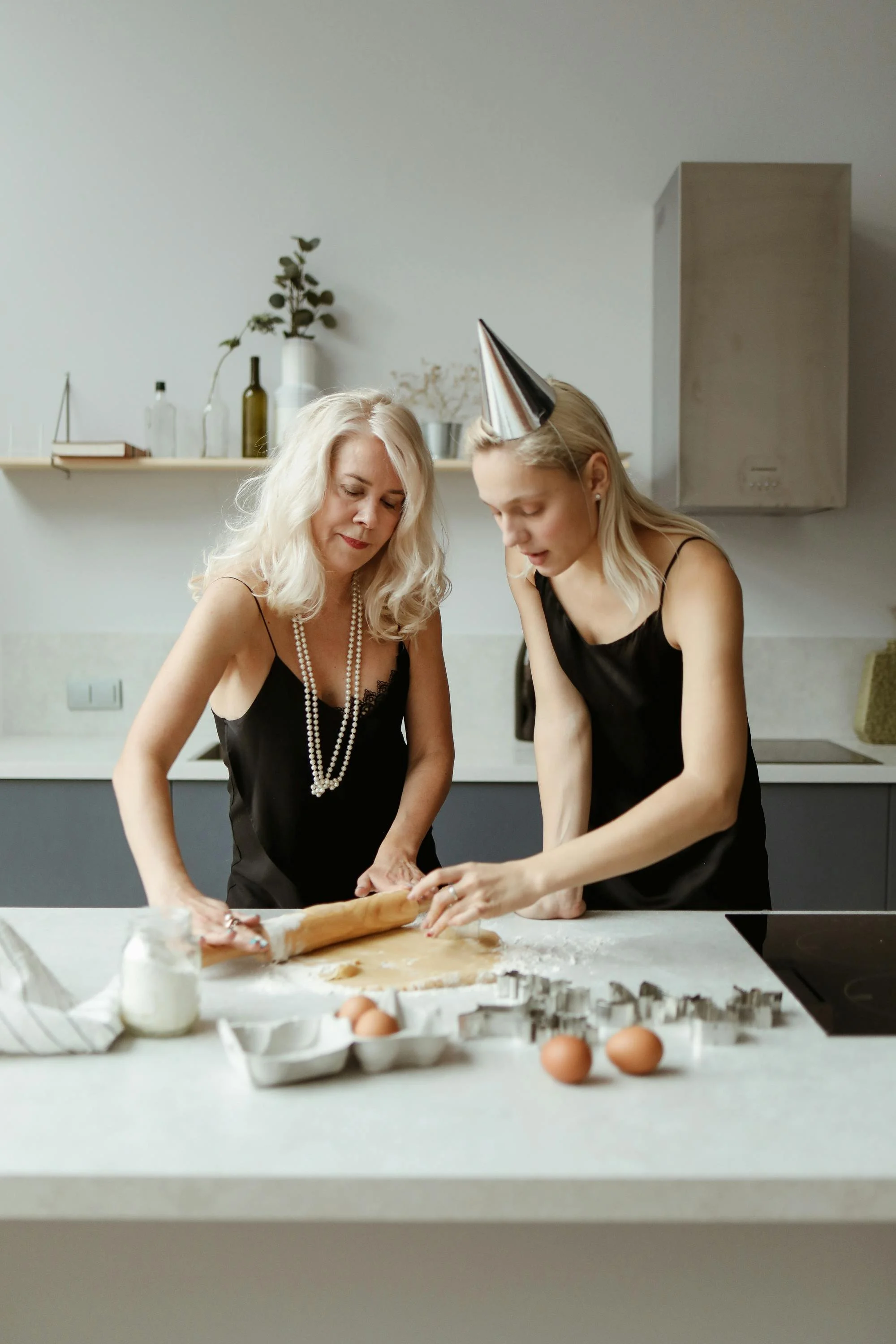 An older woman and younger woman standing close together at a celebration, sharing a tender and melancholy moment — representing the complexity of family bonds