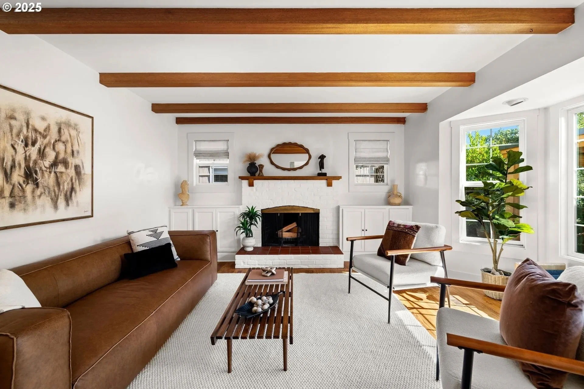 Living room with exposed beams staged in California casual style. Natural light streams through large windows, showcasing the home's potential and increasing perceived value for home buyers. 