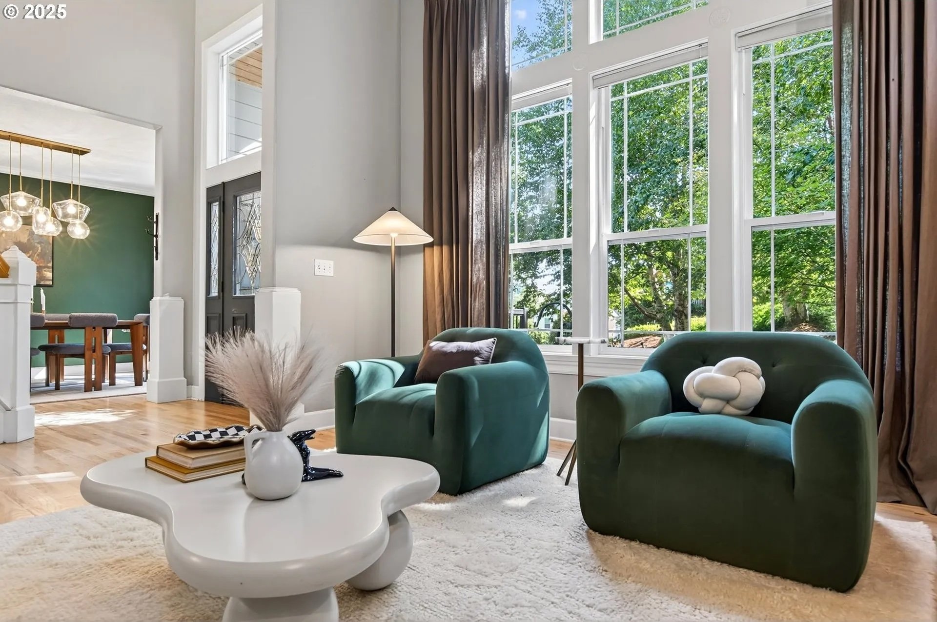 A sculptural coffee table and modern green velvet accent chairs, soaring ceilings featured in this home staging in West Linn Oregon
