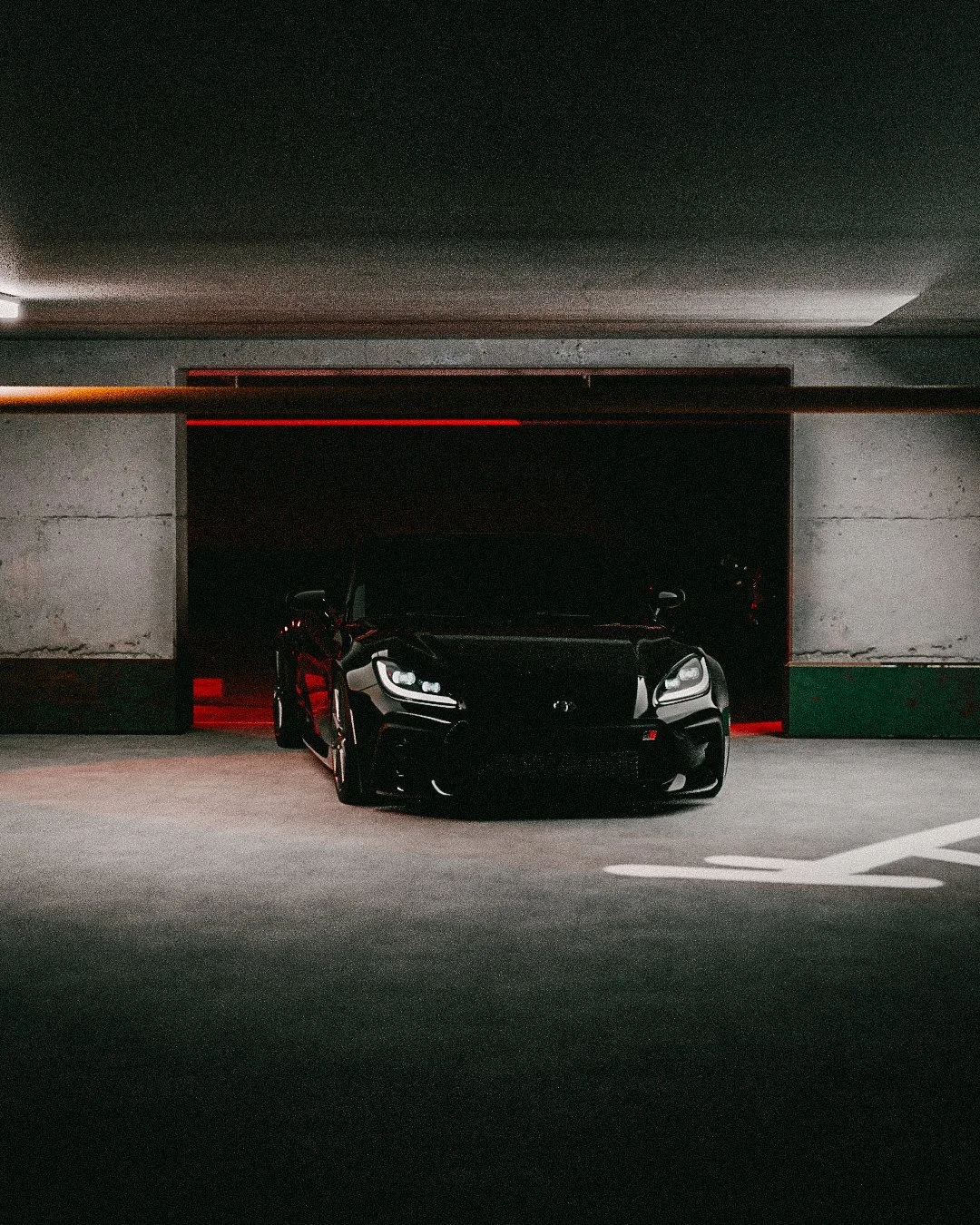 Black coupe in a garage bay with graffiti on the floor