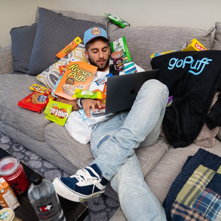 Lifestyle photo of a man relaxing with Gopuff snacks