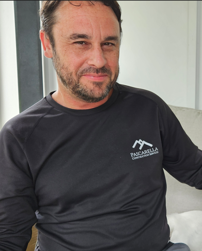 Jesse Marsh: A man with a beard and mustache wearing a black baseball cap with a star outline and a plain black t-shirt, seated in a vehicle with trees visible outside the window.
