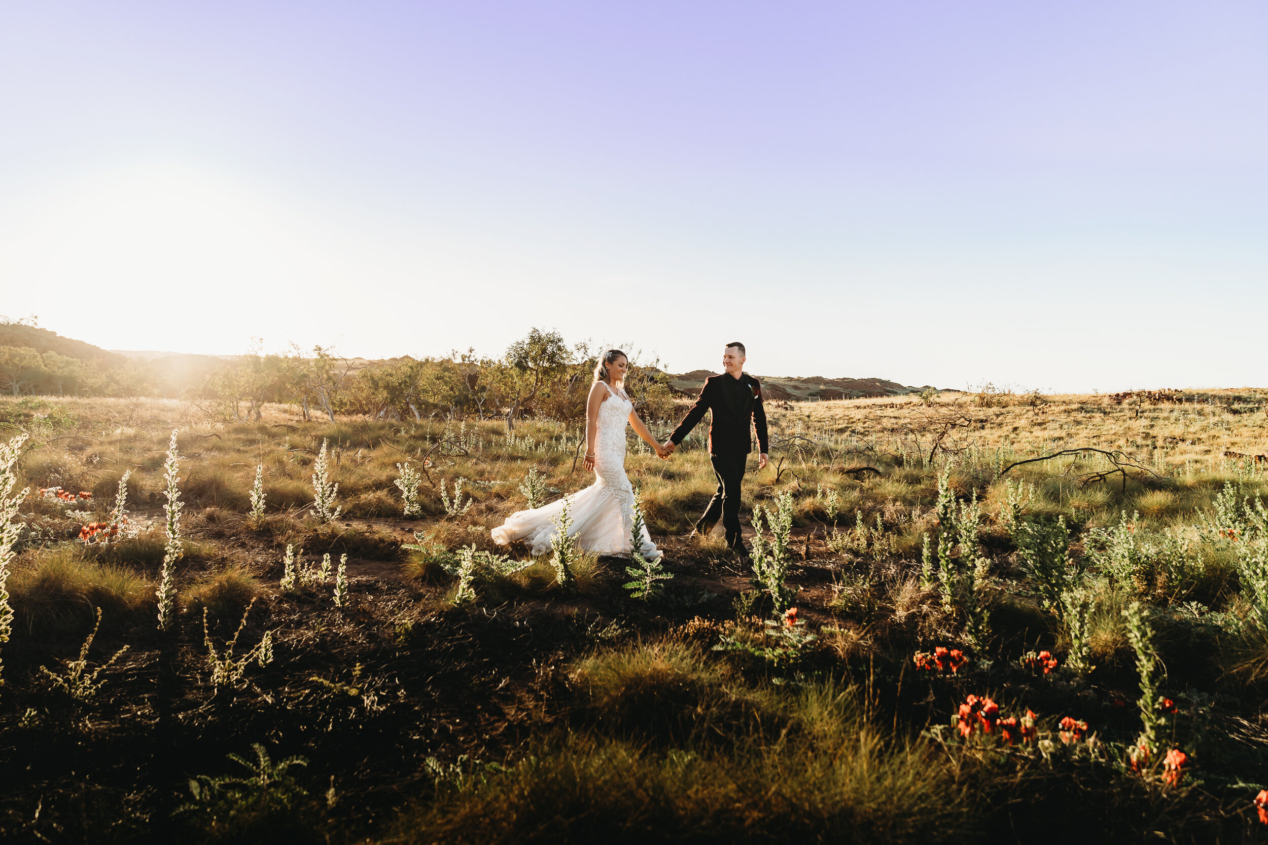 Wedding couple walking through wildflowers in open Bush landscape