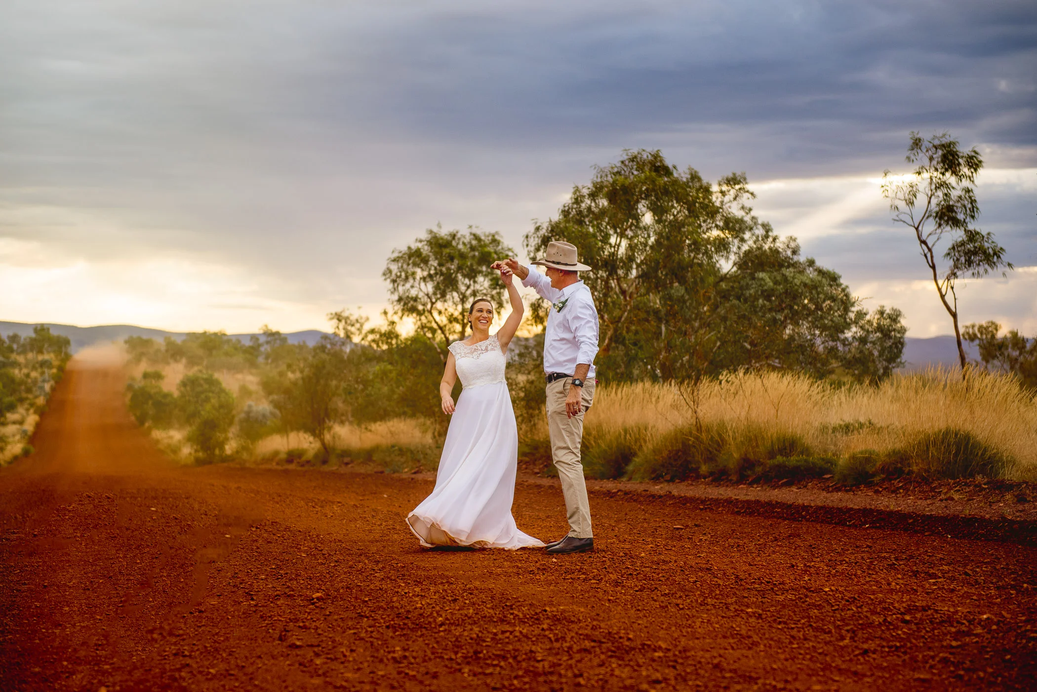 Relaxed wedding couple dancing on Karijini red dirt road in the WA bush