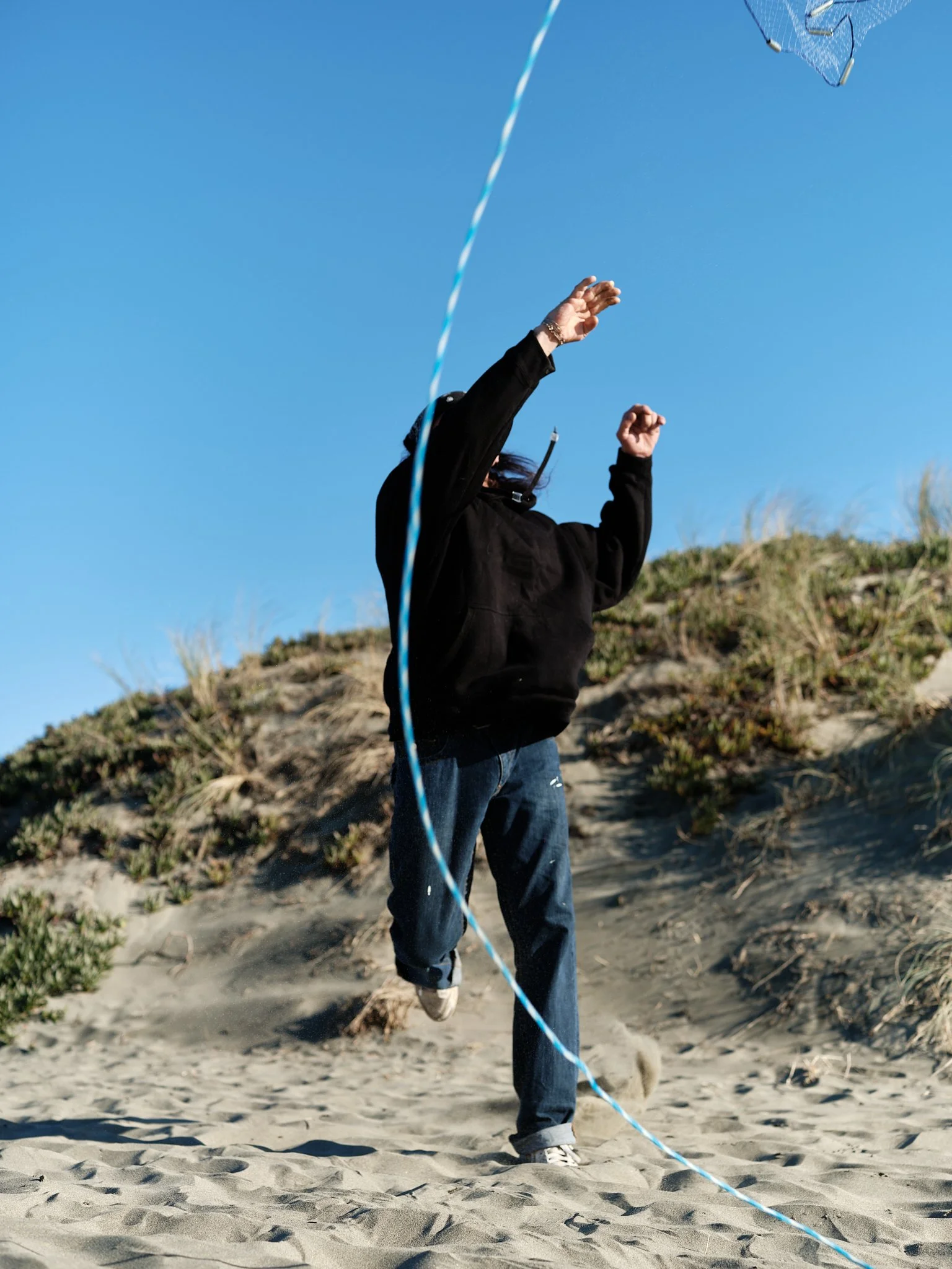 A figure casts a fishing net, leaving a blue and white rope as the primary focus. In this project, I use a line as a visual tether; a guide to help navigate unfamiliar territory. It helps me maintain a sense of direction and safety while I balance my