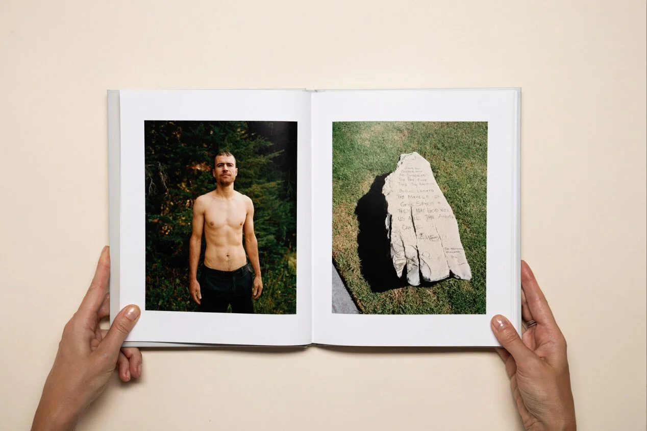 Open photo album with a shirtless man standing outdoors on the left page and a carved stone with inscriptions on the right page.