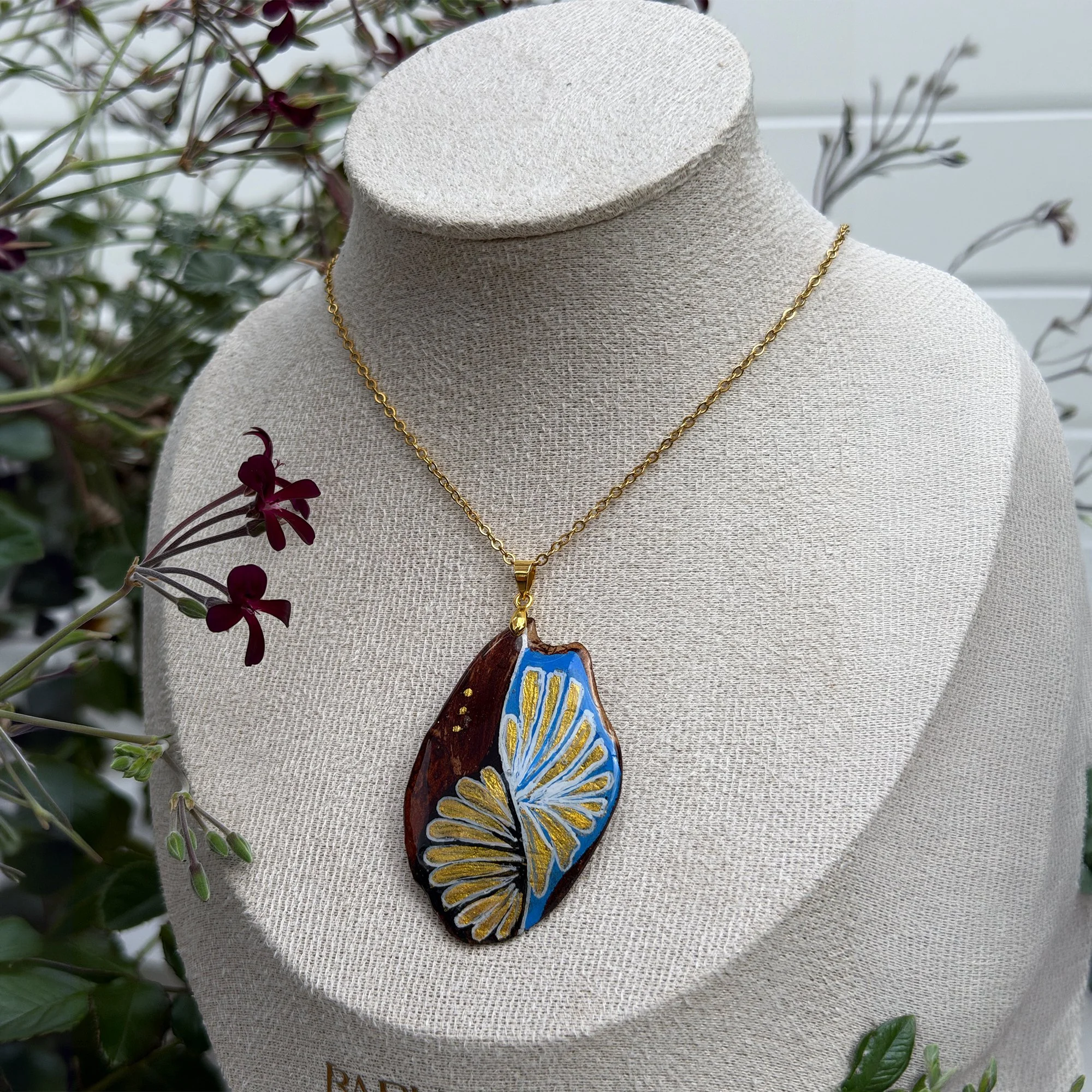 Celestrina azure blue bark pendant necklace worn on model with purple flowers