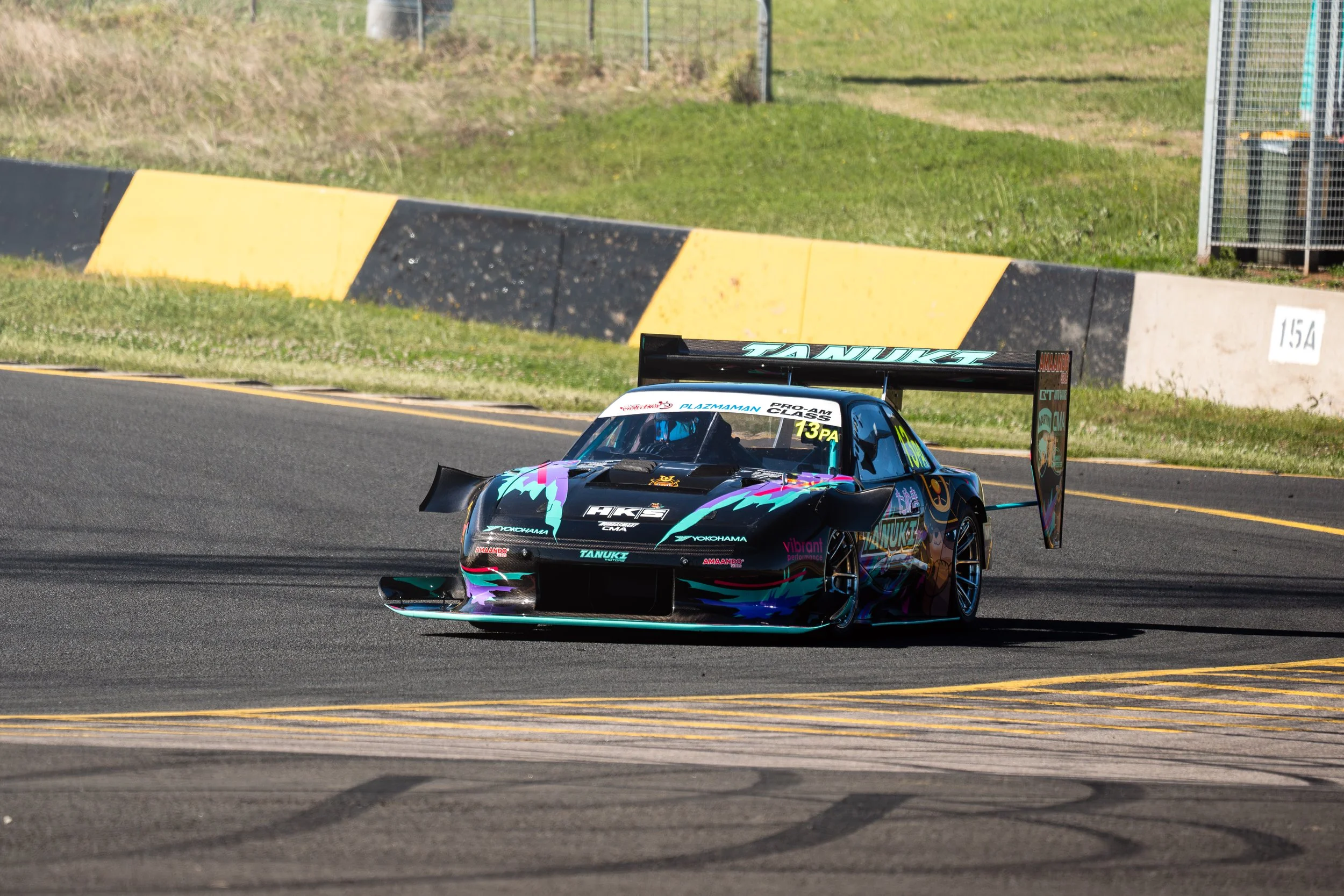 A race car on a track with a colorful, aerodynamic design and a large rear wing.