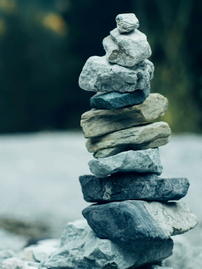 Stacked rocks on a smooth surface outdoors with a blurred natural background.