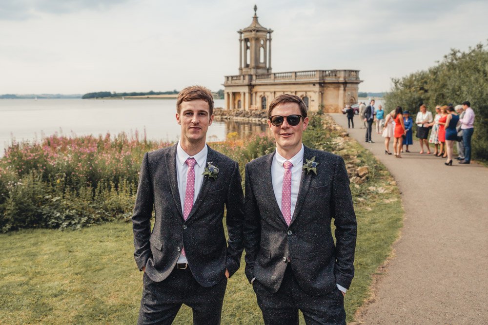 Groom and best man stand in front of Rutland Water