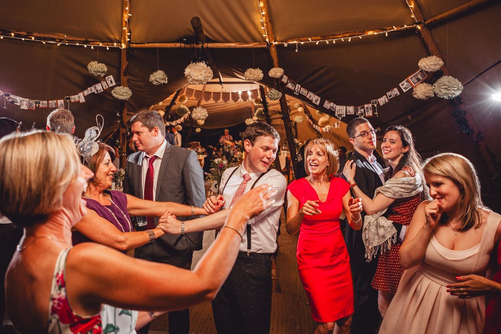 groom dances with guests at tipi wedding