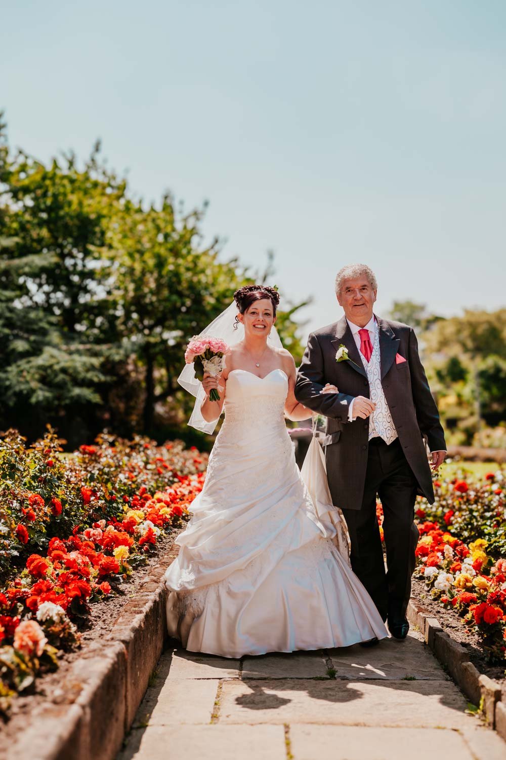 father and bride walk along path to church