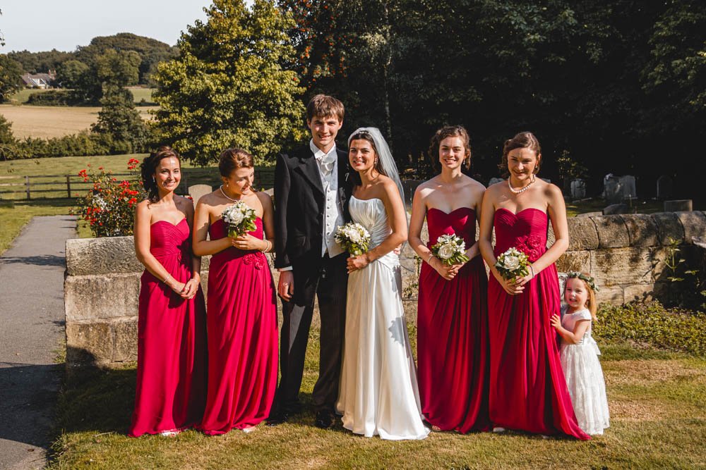 bride and groom pose with bridesmaids in Quarndon churchyard, Derby