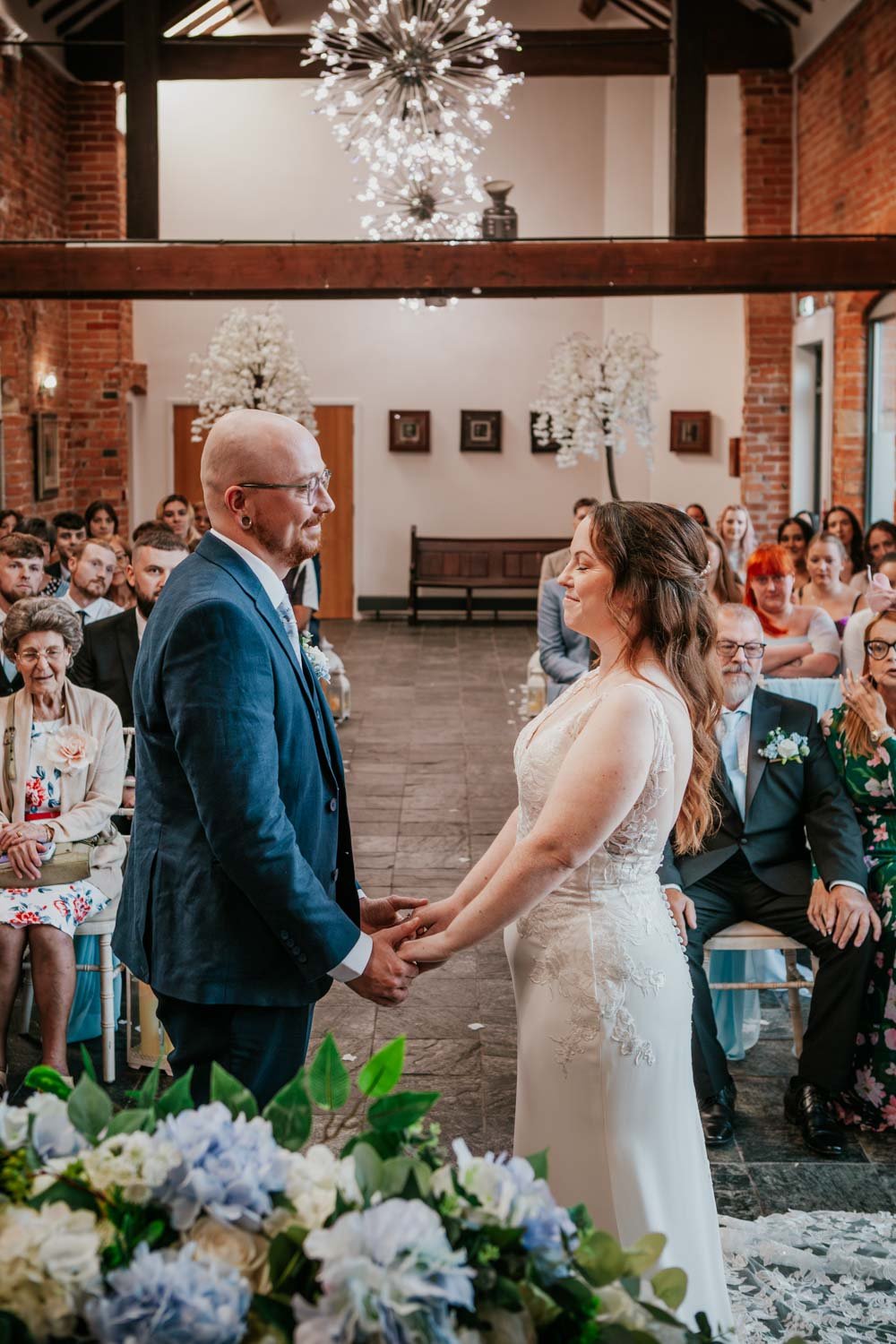 bride and groom hold hands at the altar
