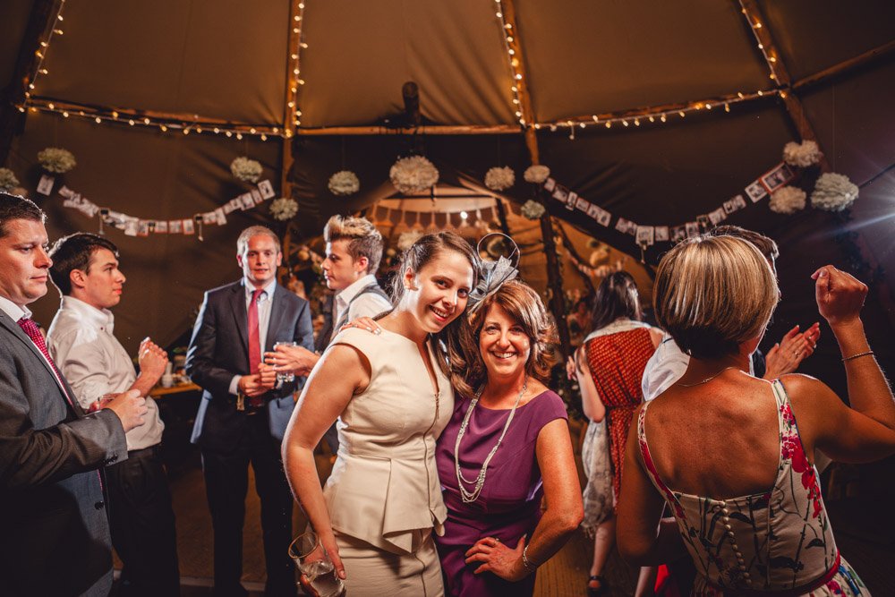 guests pose on the dance floor at a tipi wedding