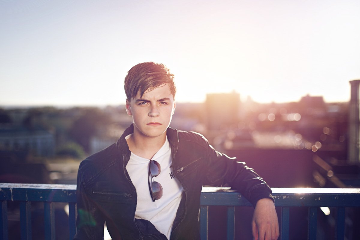 young singer songwriter Ben Pryer stands in a city at sunset