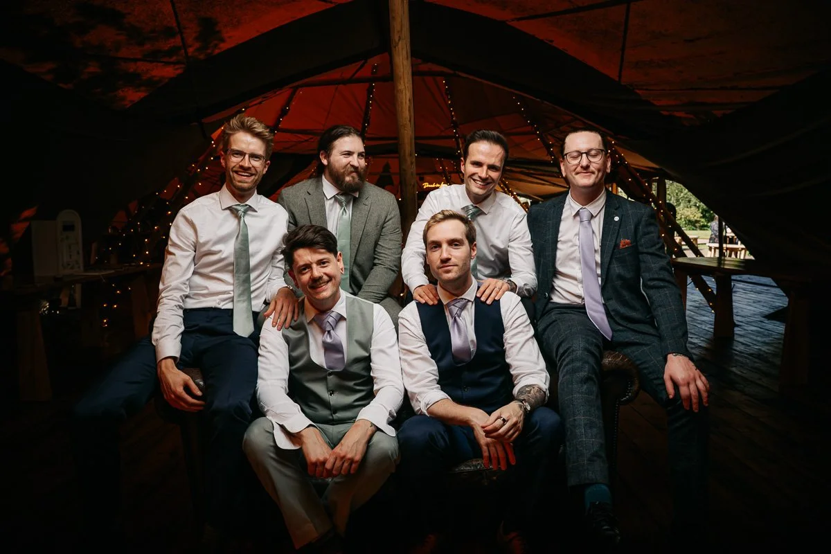 Groomsmen pose for a group portrait in the tipis at Whatton House, Leicestershire